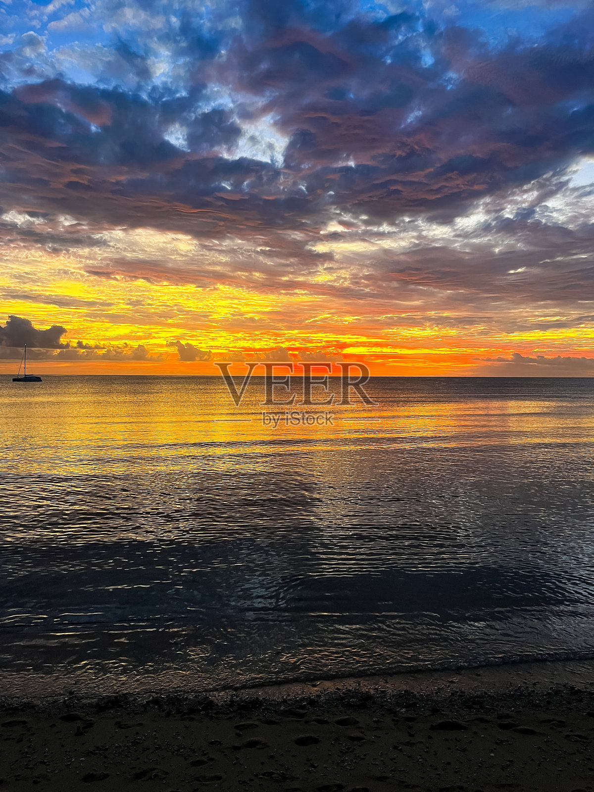 壮观的热带日落用鲜艳的色彩照亮了地平线,海洋在阴云密布中闪耀。照片摄影图片