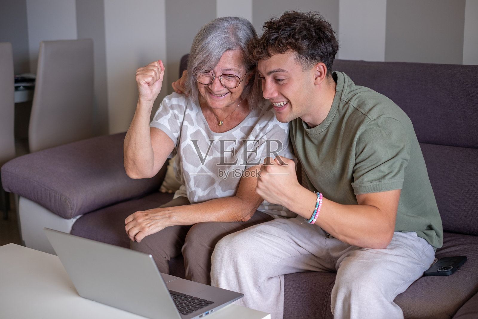 热情的多代家庭成员一起坐在沙发上观看足球锦标赛,开心的孙子与祖母庆祝球队胜利。照片摄影图片