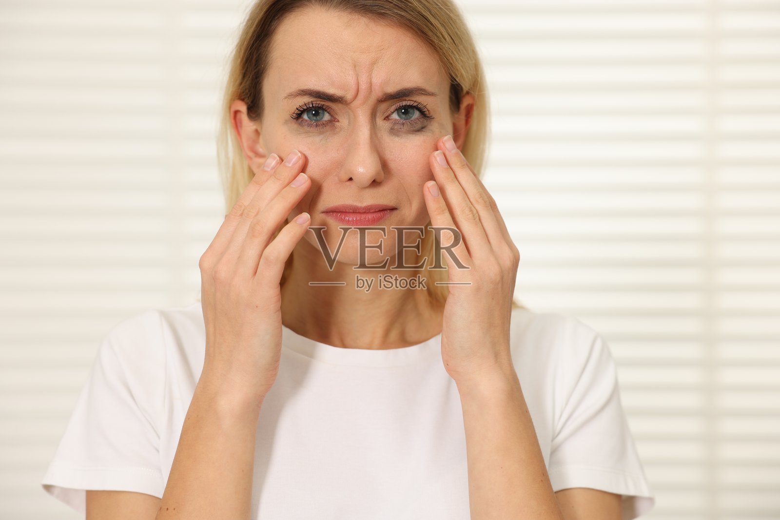 在室内哭泣的悲伤女性,眼线晕染。照片摄影图片