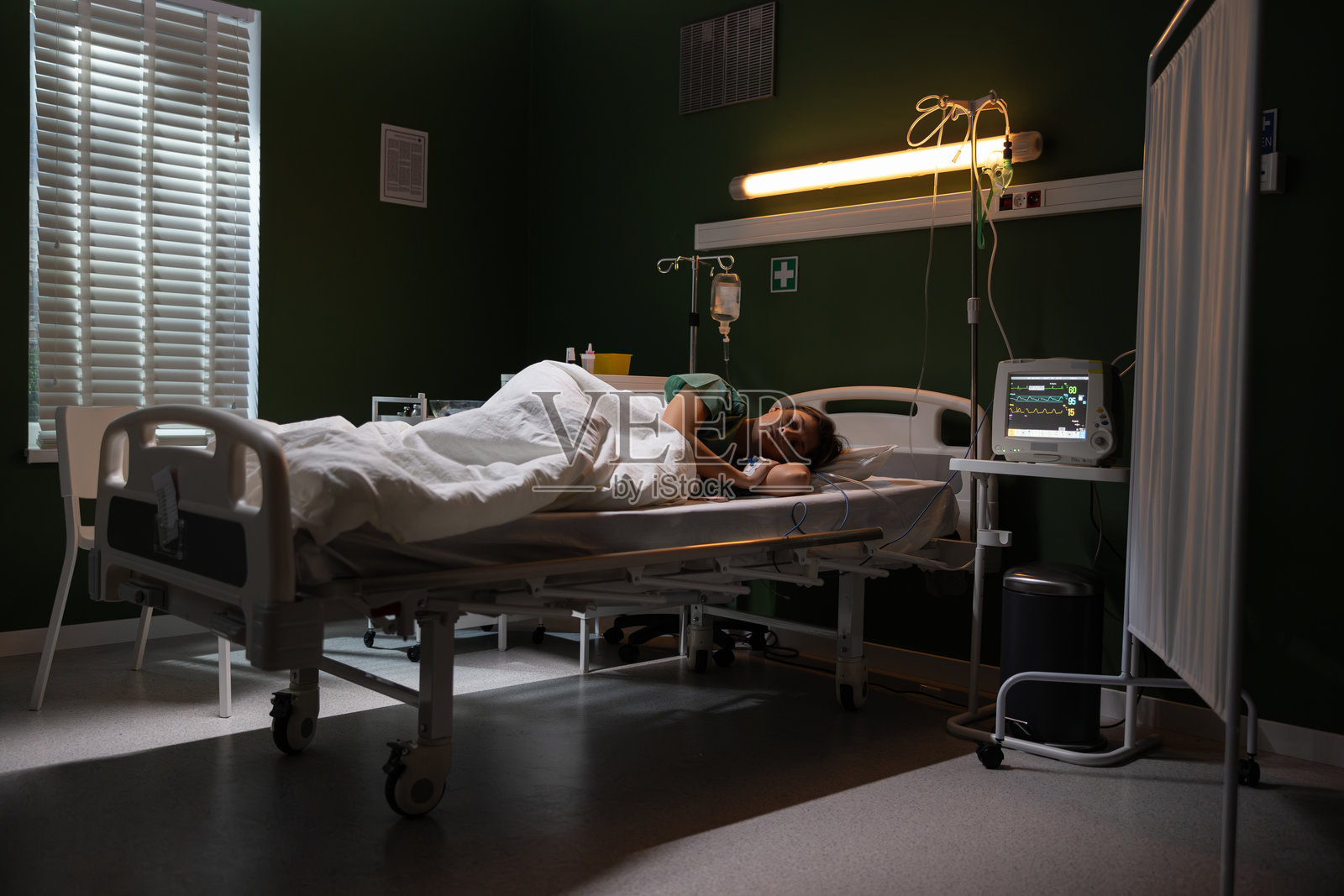 女孩躺在医院病床上,手上插着导尿管。照片摄影图片