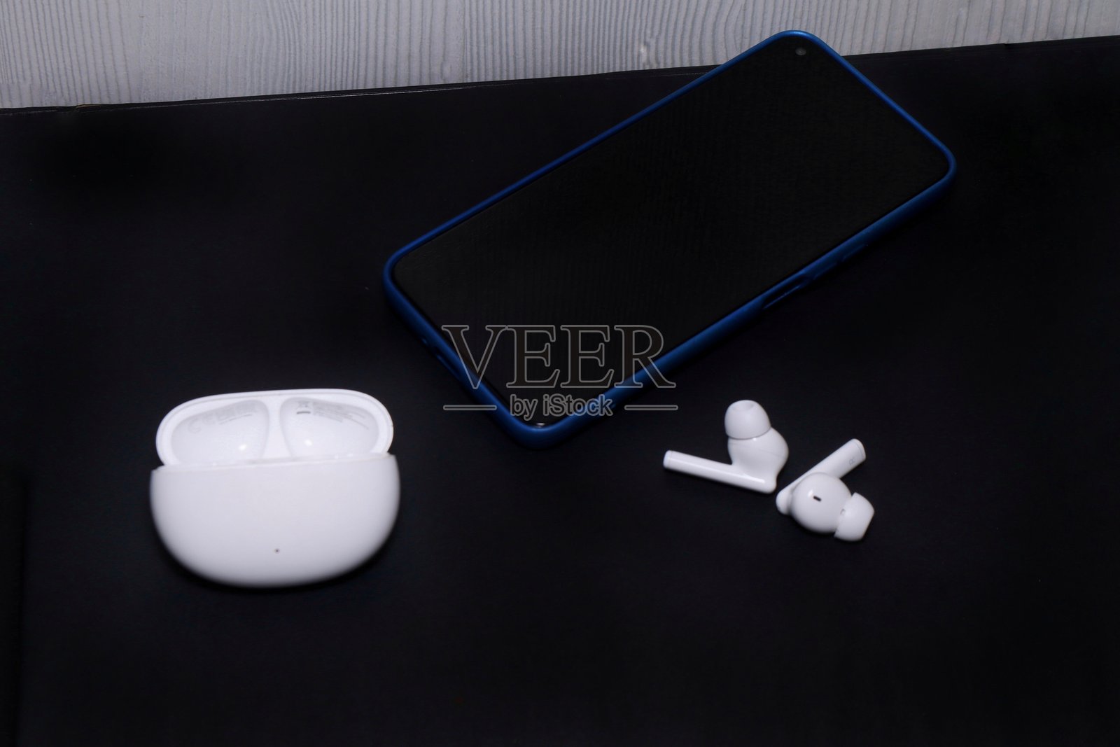 黑色表面上的智能手机和耳塞。照片摄影图片