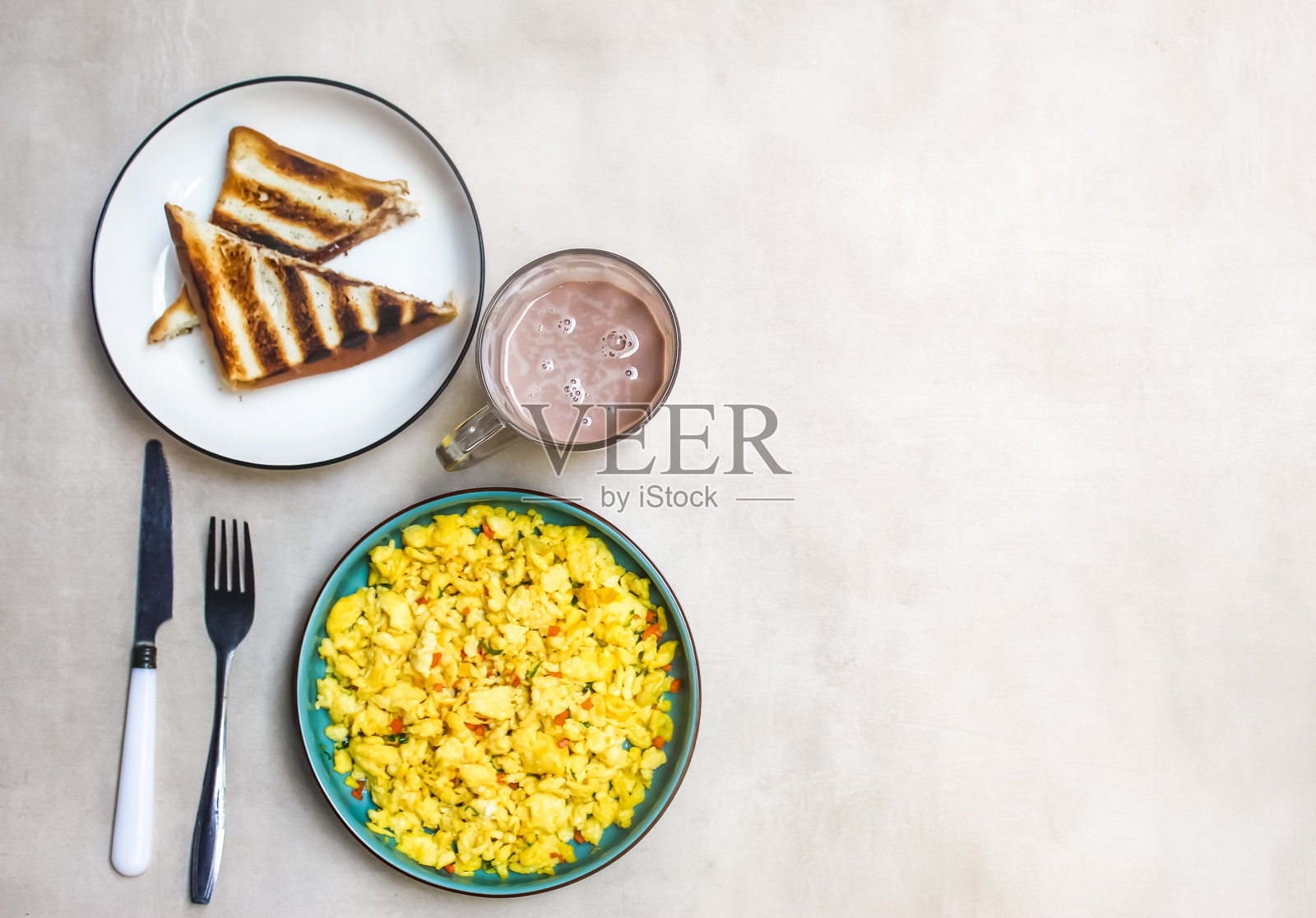 桌子上摆放着炒鸡蛋、吐司和巧克力牛奶,形成早餐菜单,留有负空间。食品摄影。食品背景。照片摄影图片