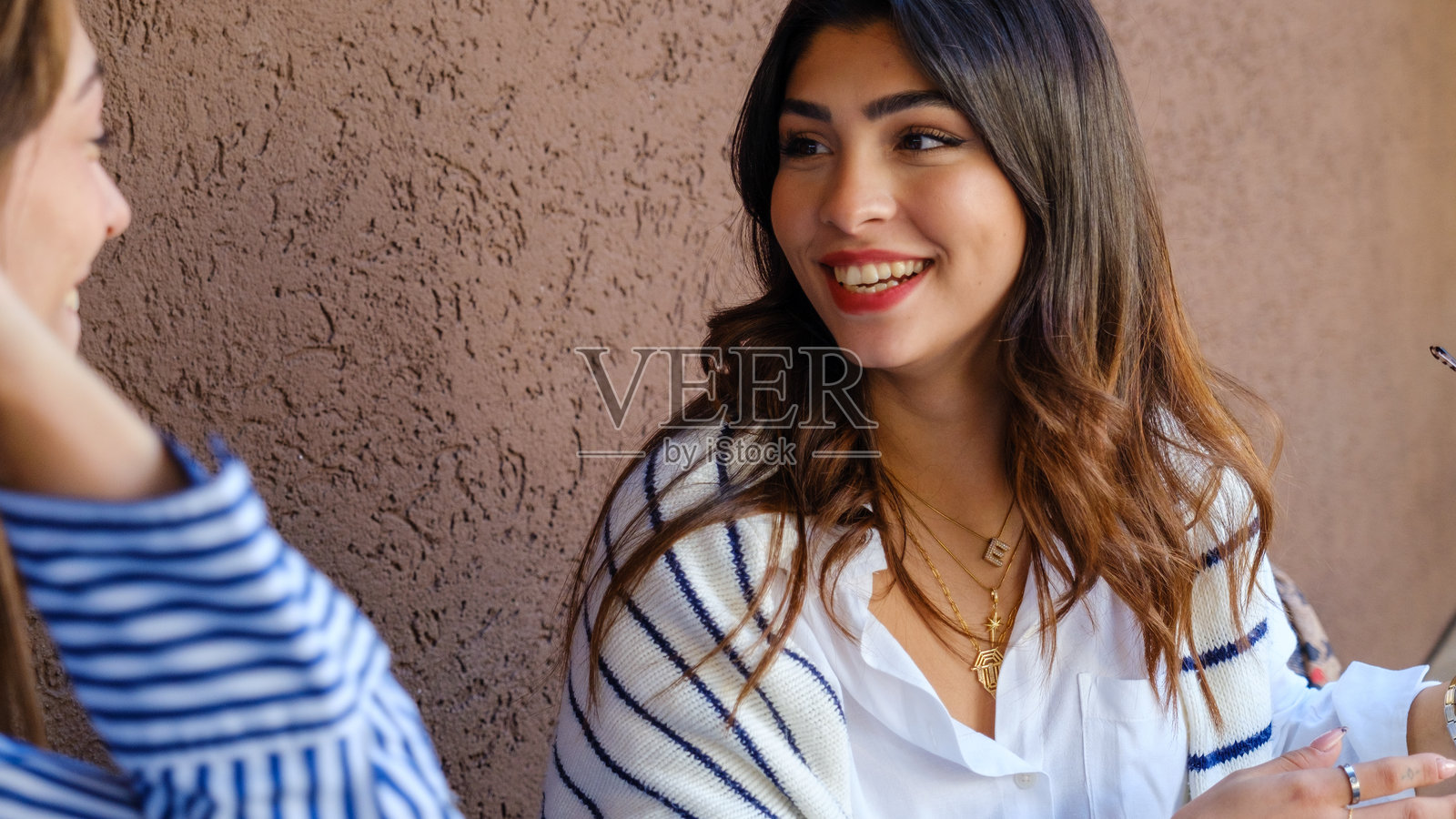 两个年轻女性朋友在夏日的咖啡馆里愉快地聊天。照片摄影图片