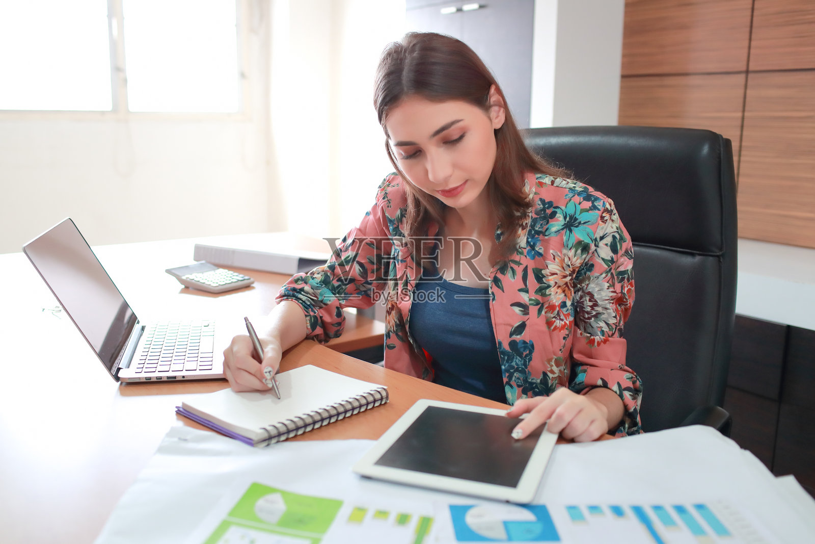 女商人在桌子上写书的同时使用数字平板电脑照片摄影图片