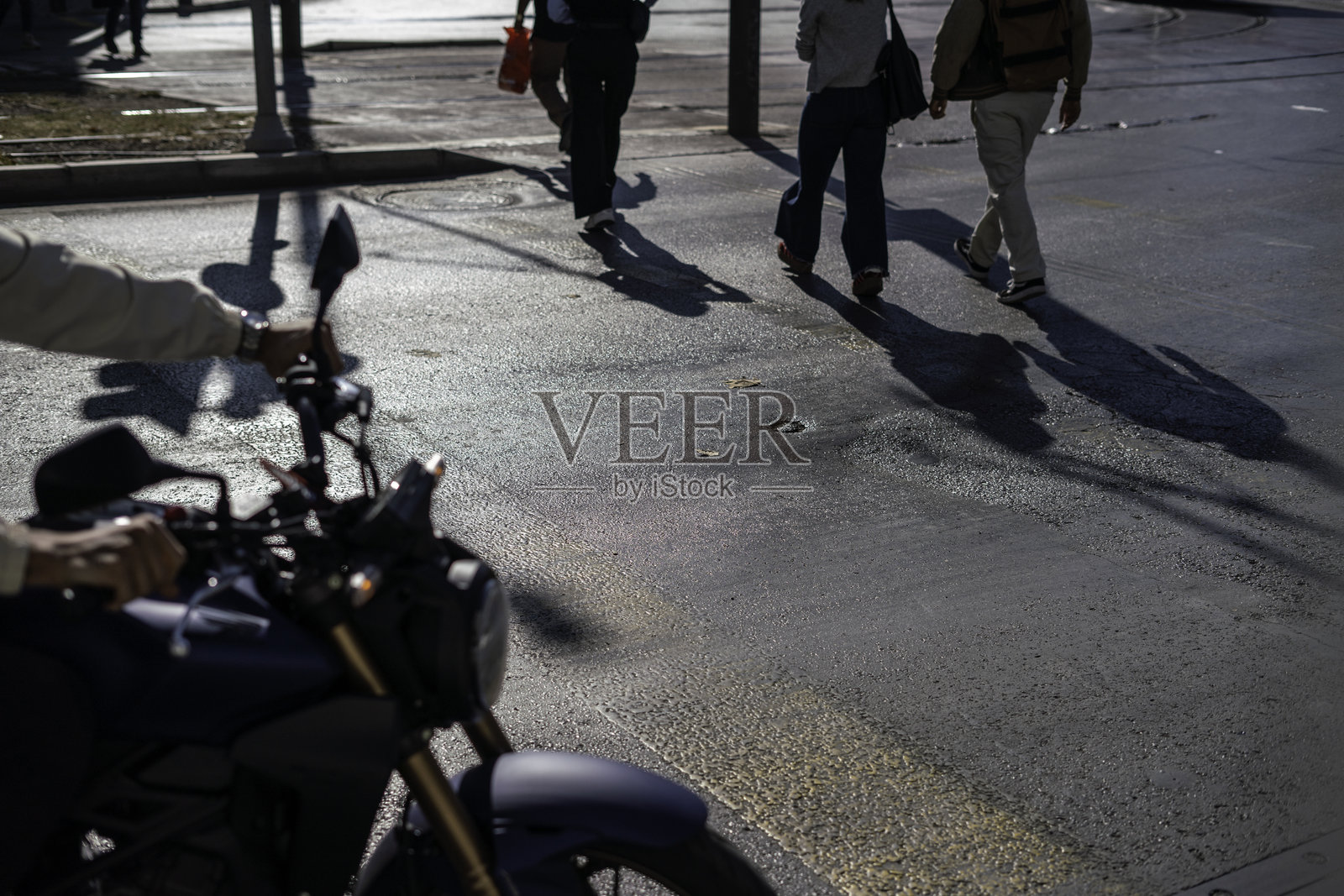 行人正在过马路,摩托车在街上,横向街道静止不动。照片摄影图片