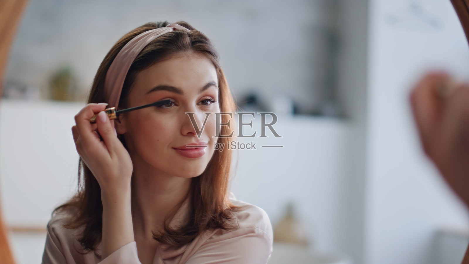 微笑的女士在早晨美容程序中涂抹睫毛膏特写。宁静的女性照片摄影图片