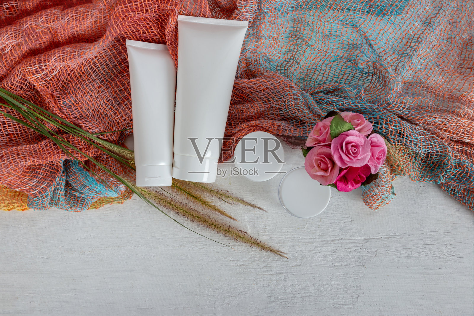 从上方拍摄的美容产品与桌上的人造花照片摄影图片