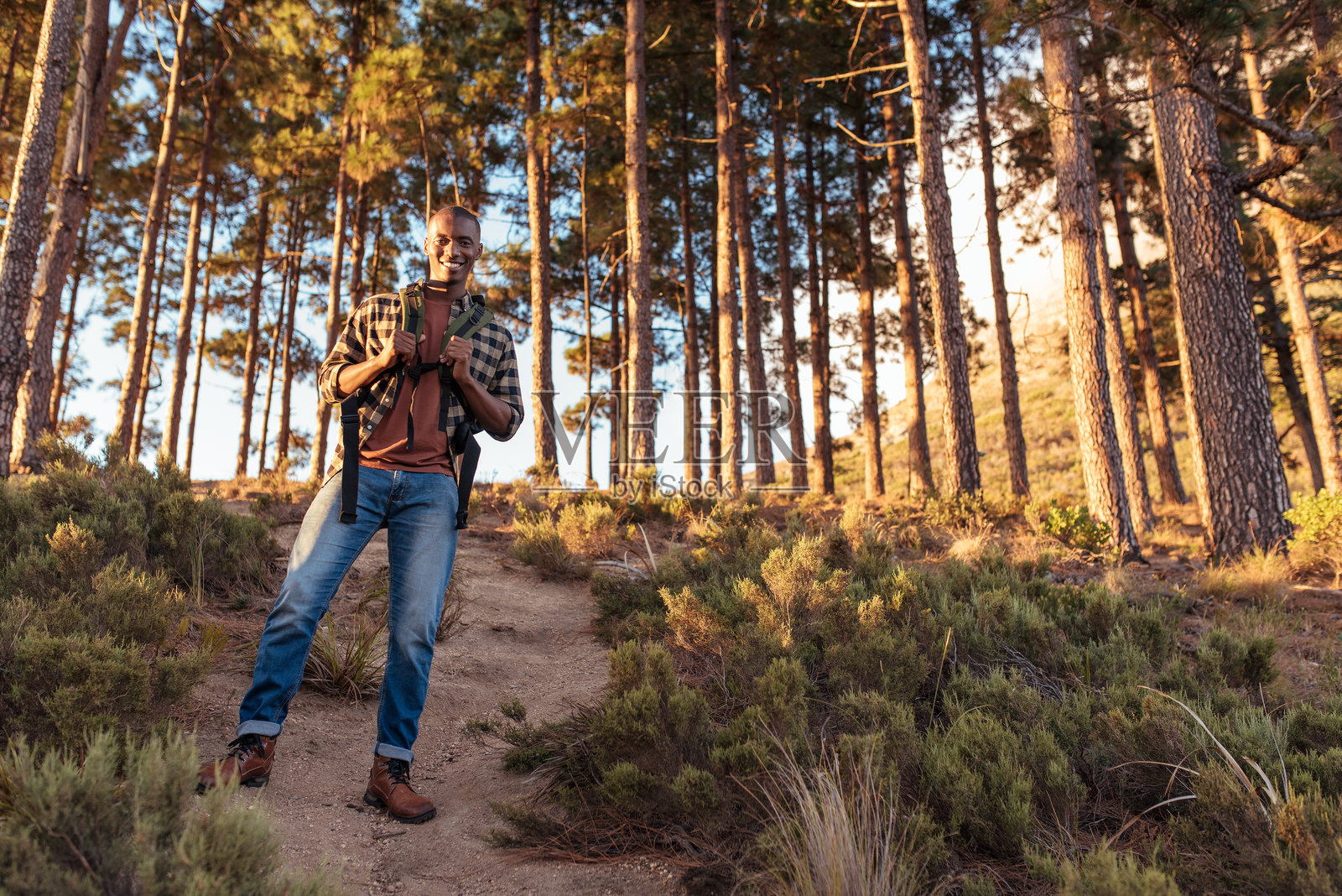 微笑的非洲男子站在森林小径上照片摄影图片