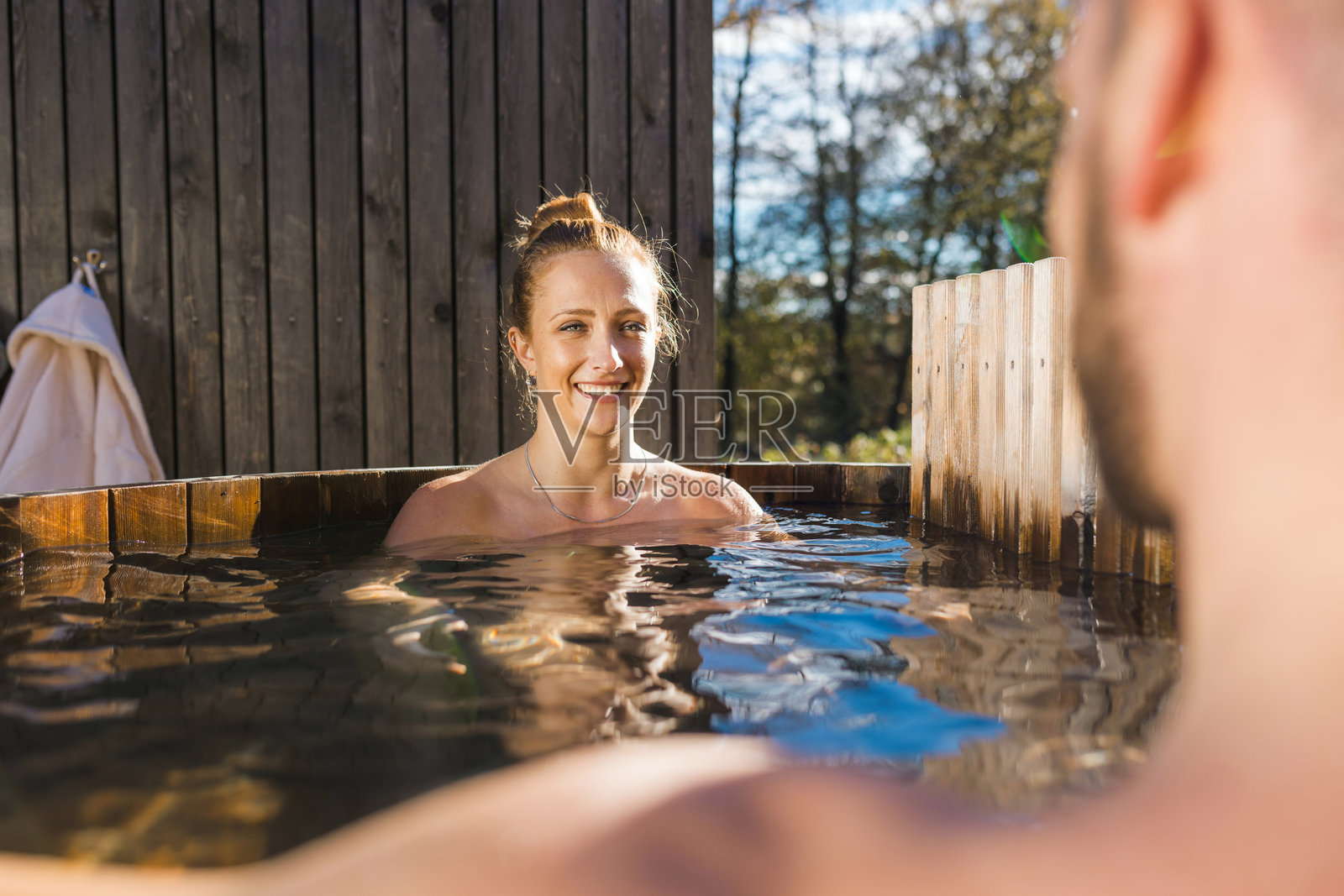 年轻情侣脱下浴袍,走进私人户外热水浴缸照片摄影图片