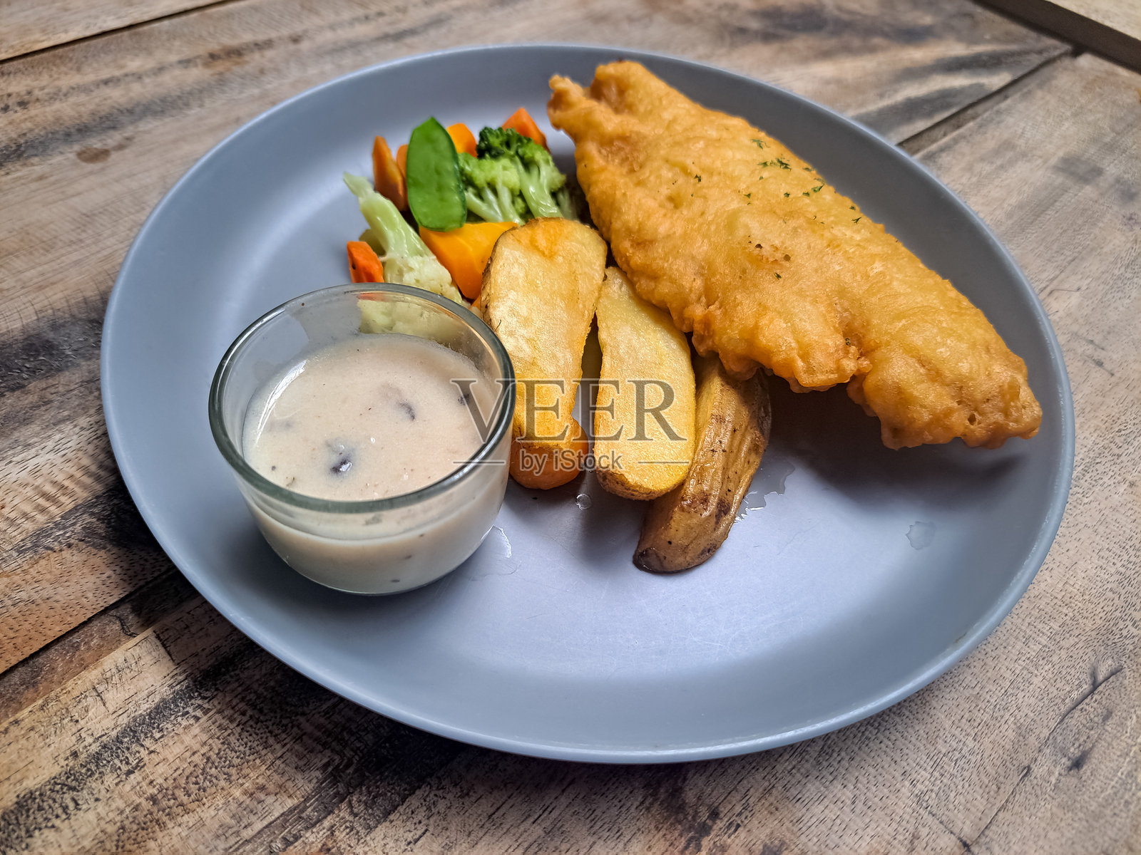 鱼和薯条配奶油蘑菇酱和蔬菜的餐盘。菜单。照片摄影图片