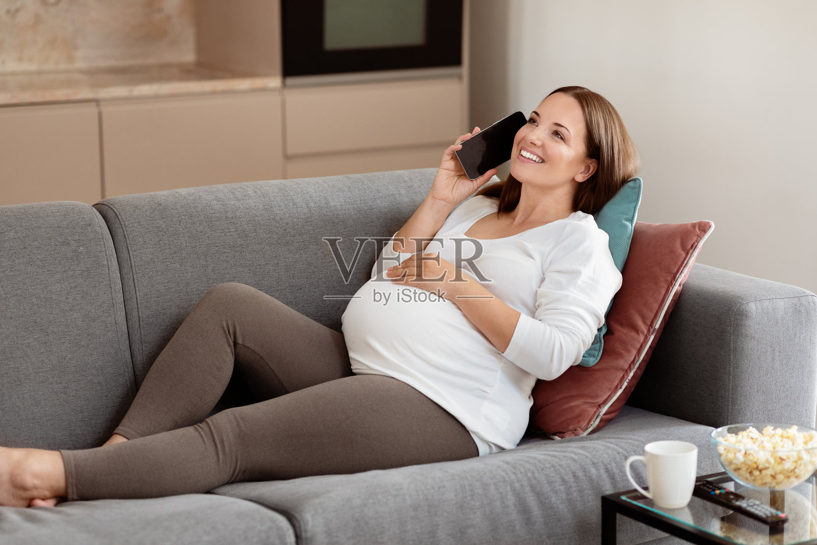 孕妇在家中沙发上放松,边打电话边使用智能手机照片摄影图片