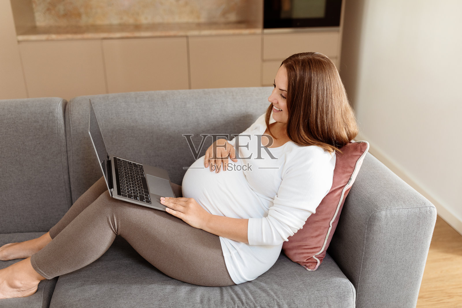孕妇在现代客厅的沙发上放松时使用笔记本电脑工作照片摄影图片