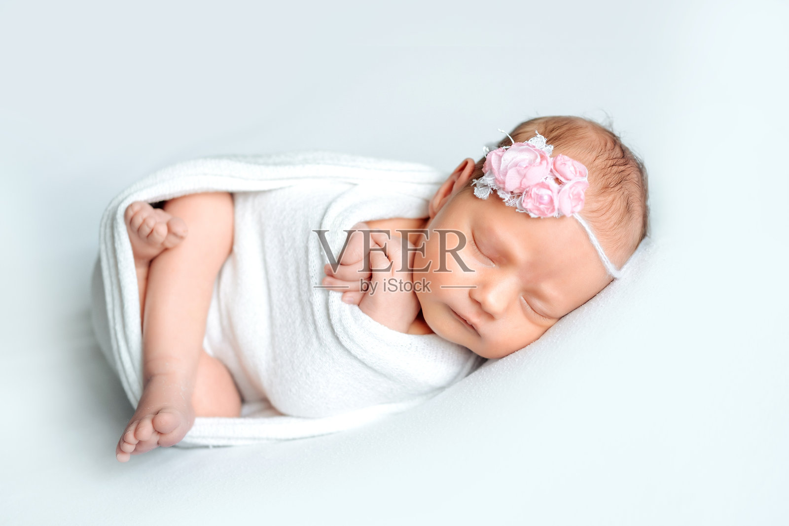 一个新生女婴在白色背景上,穿着尿布,甜美地睡着,留有文字空间,来自产房的宝宝照片摄影图片