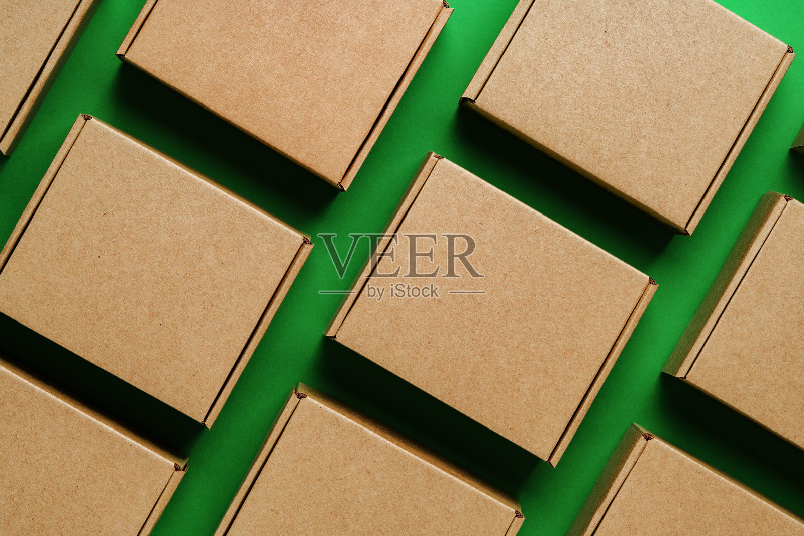 棕色纸箱排列在鲜艳的绿色表面上照片摄影图片
