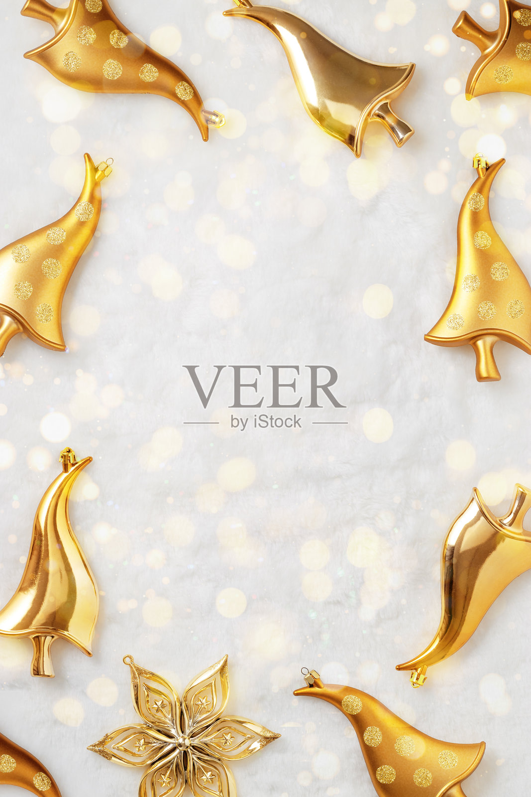 新年前夕假日框架,闪亮的金色圣诞装饰蘑菇,白色毛绒背景上的闪烁星星和散景灯光。闪耀的节日装饰圣诞树,留白背景。照片摄影图片