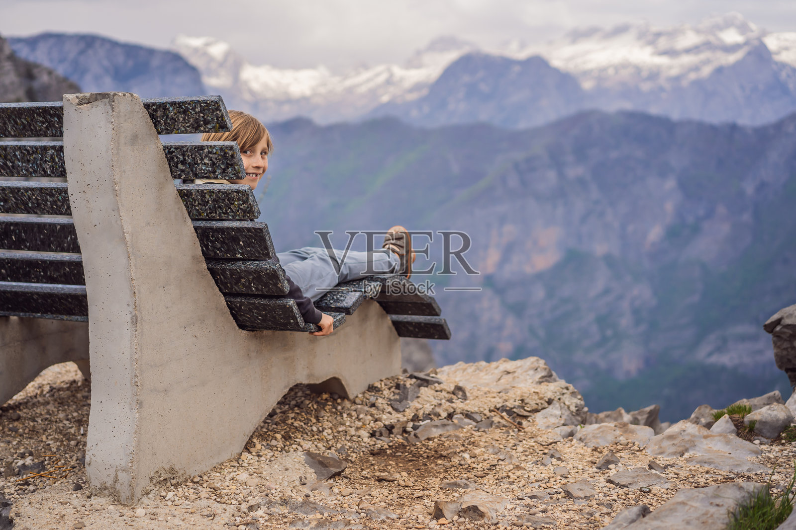 男孩游客在黑山格尔洛索科洛沃峡谷的壮丽全景背景下。前景是一座山,平坦的一侧形成悬崖,山脊上长满了树木。黑山旅行的概念。照片摄影图片