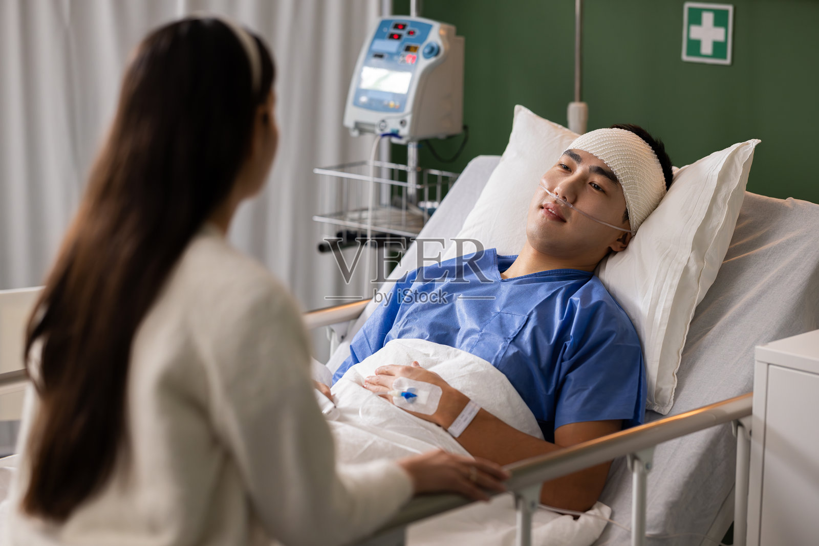 男人专注地倾听妻子安慰的话语,满怀感激与爱意地看着她,医院的病房里充满温馨。照片摄影图片