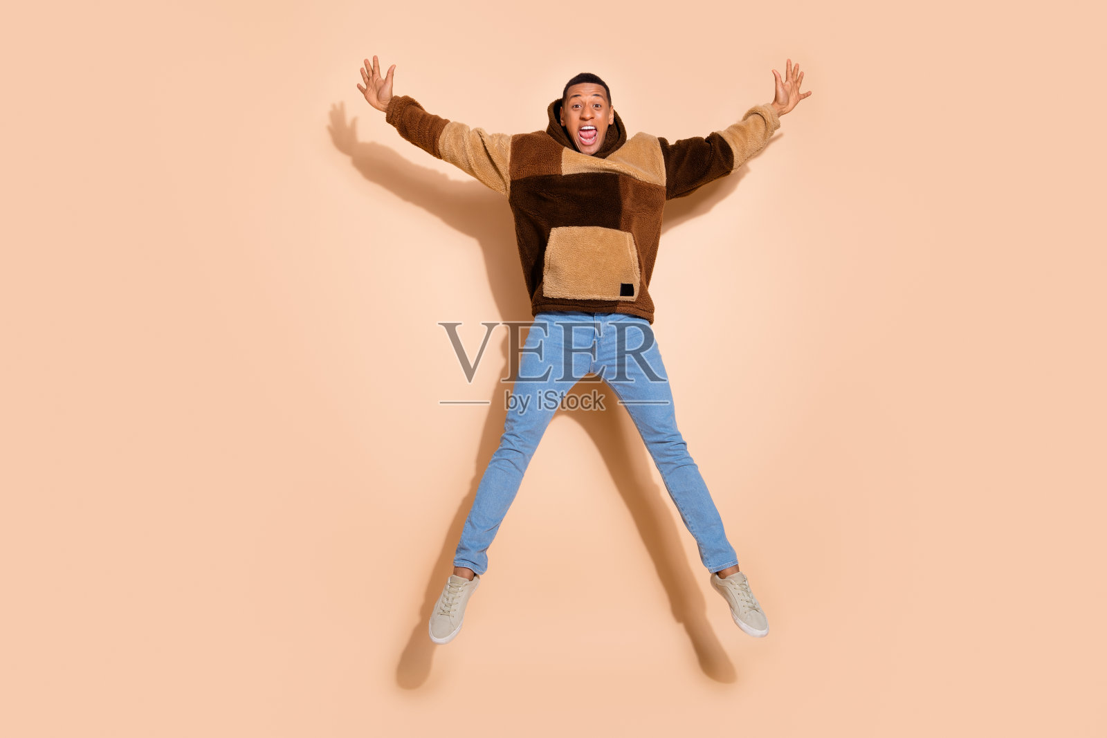 穿着时尚的积极男士在米色背景上庆祝成就,心情愉快。照片摄影图片