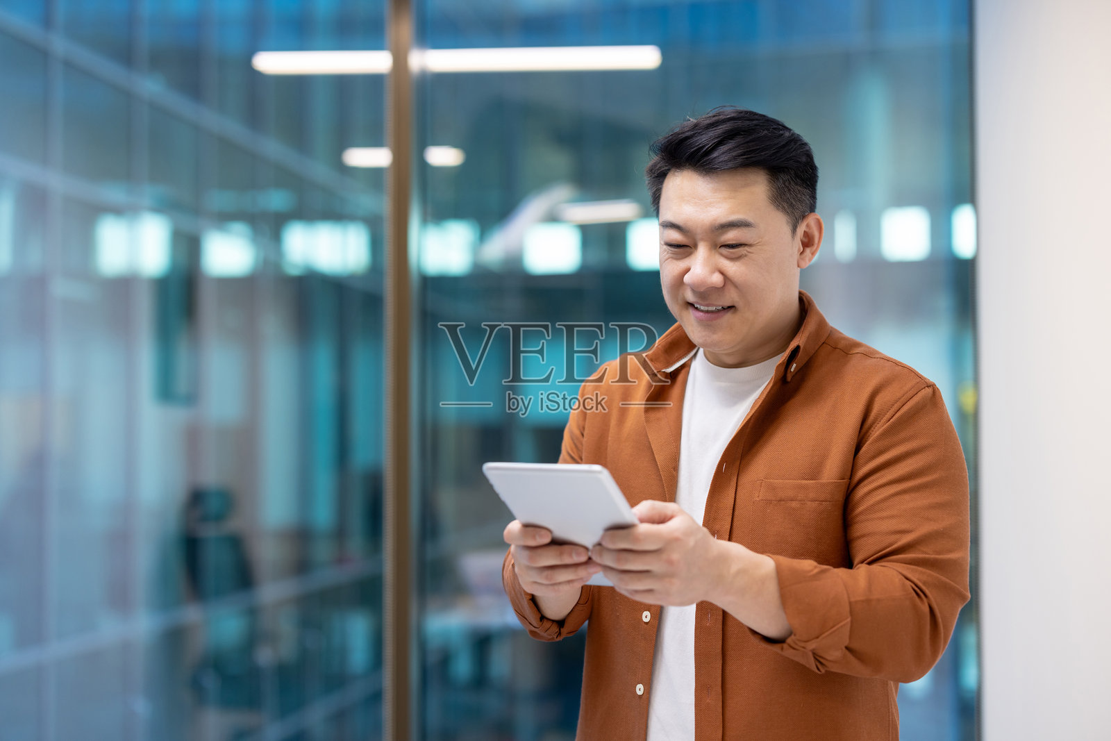 现代办公室中的亚洲商人使用平板电脑进行工作沟通与协作照片摄影图片