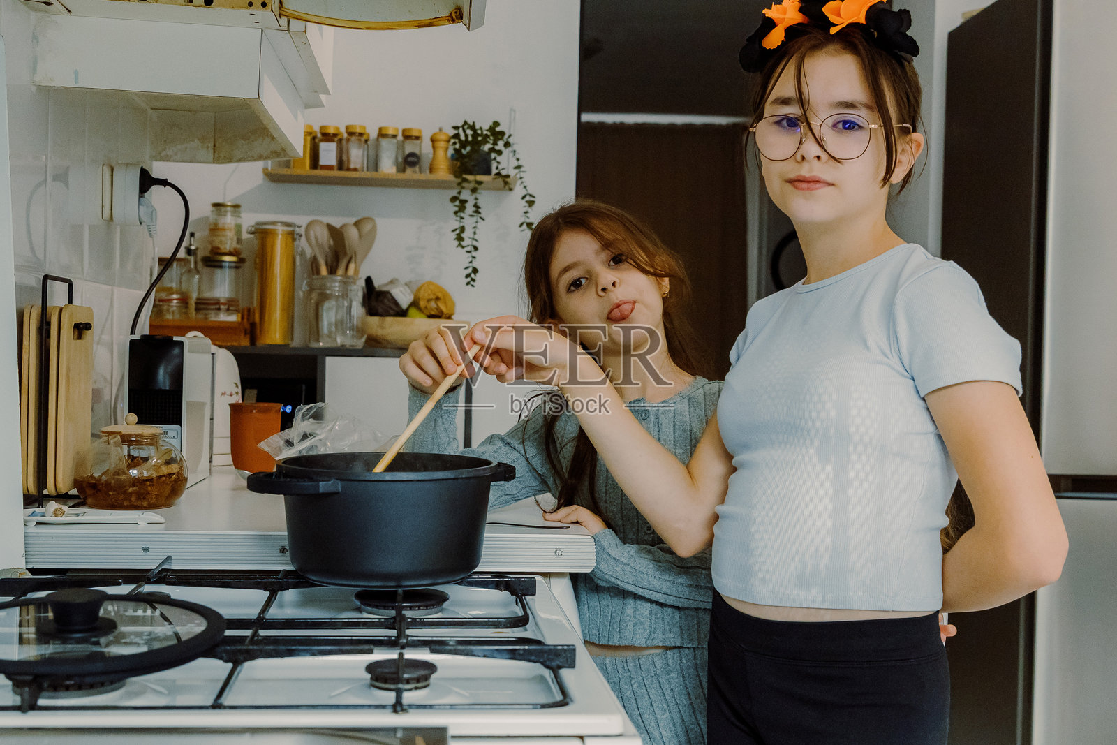 两个女孩在厨房里做万圣节意大利面。照片摄影图片