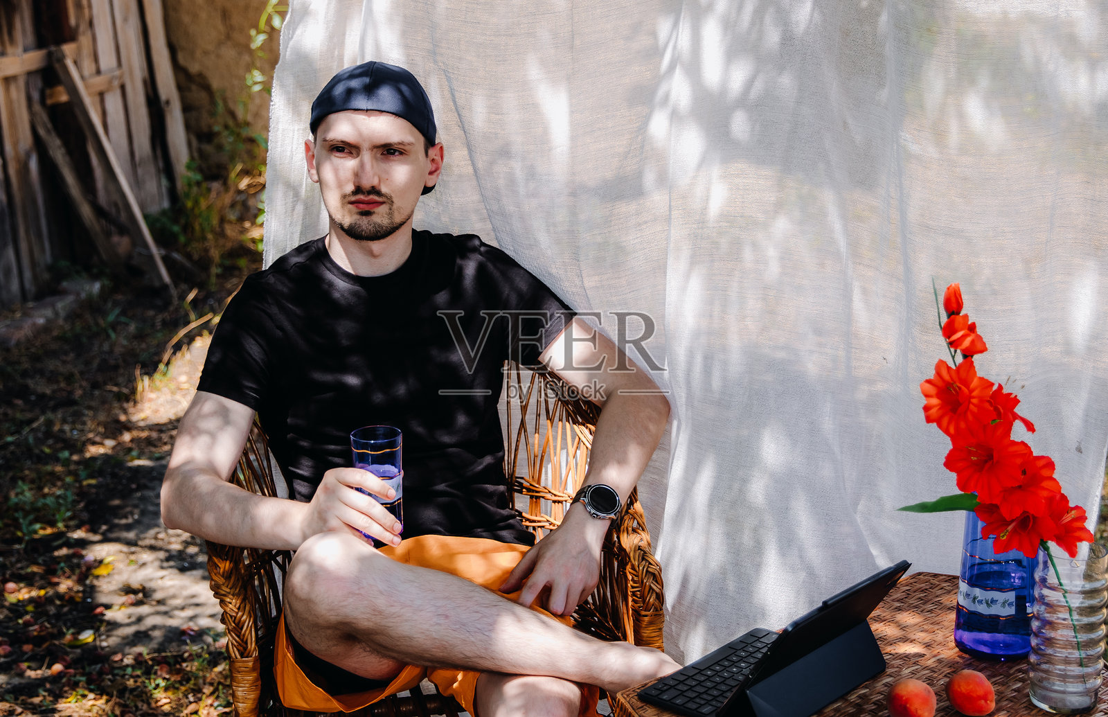 年轻帅气的男士在花园里手持一杯水的肖像。照片摄影图片