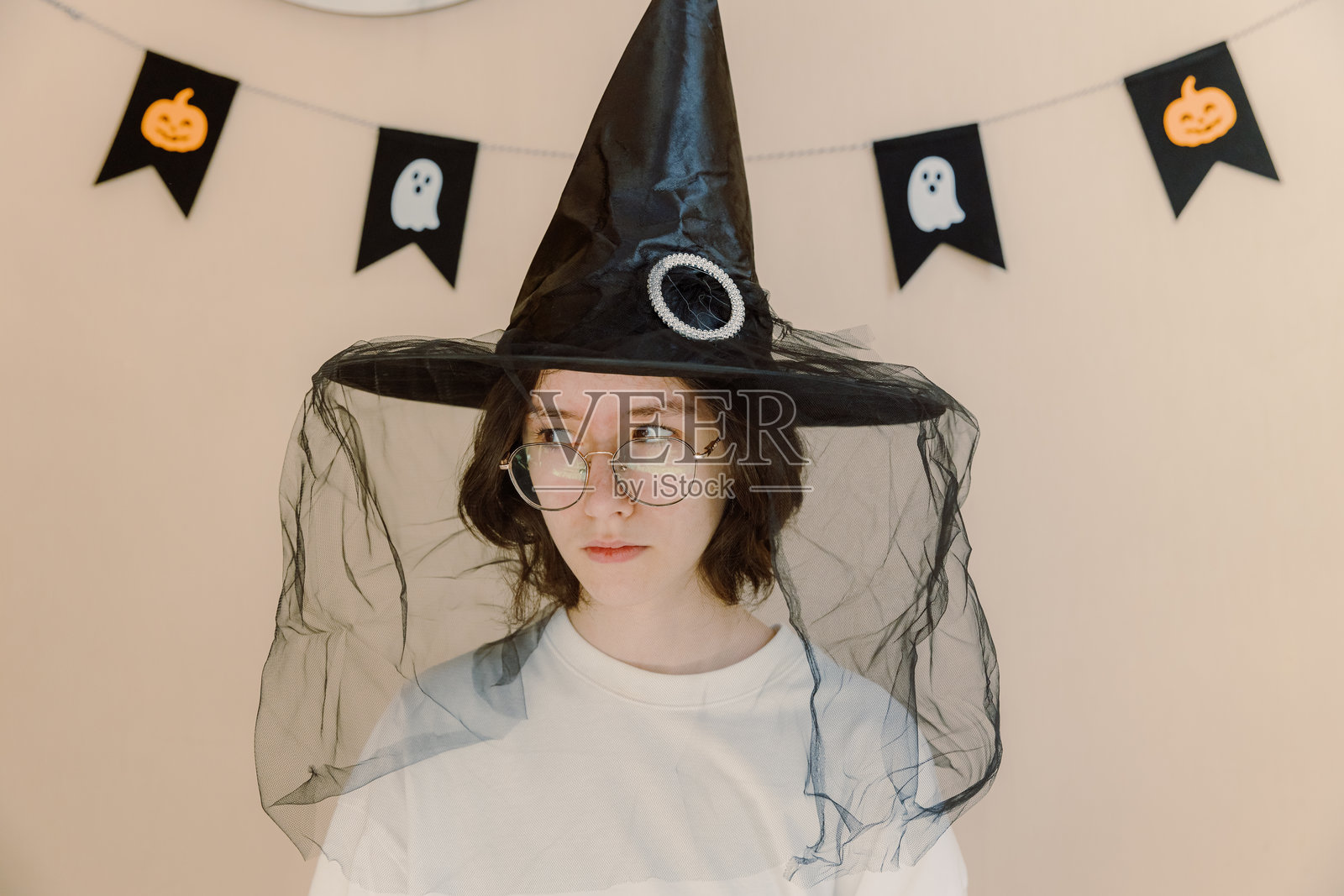 戴着巫师帽的少女露出狡黠的表情。照片摄影图片