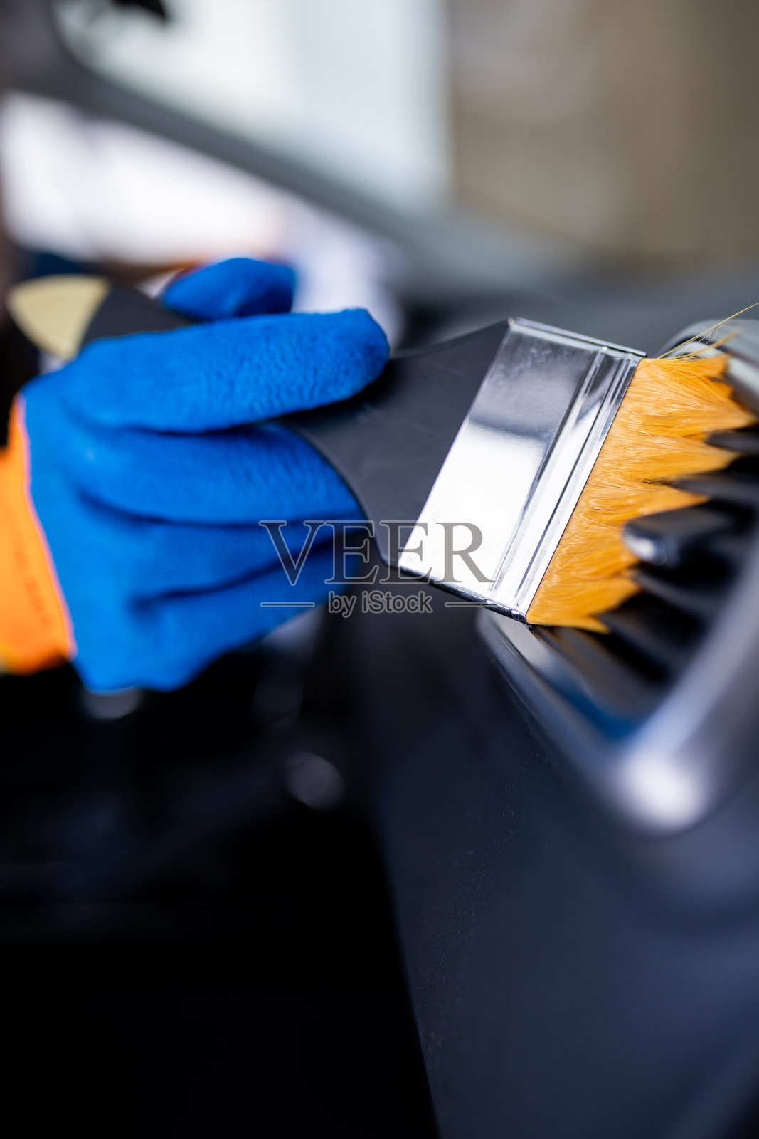 专业的汽车美容师使用刷子清洁车辆内部的空调出风口,展现出对清洁的细致关注。照片摄影图片