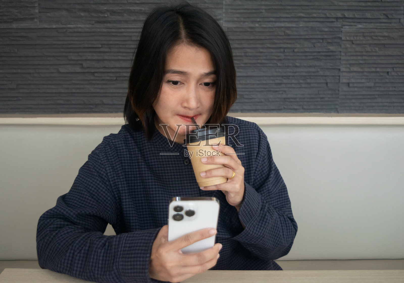 女性坐在咖啡馆里,使用手机社交媒体,同时享受咖啡,放松度假生活方式的概念照片摄影图片