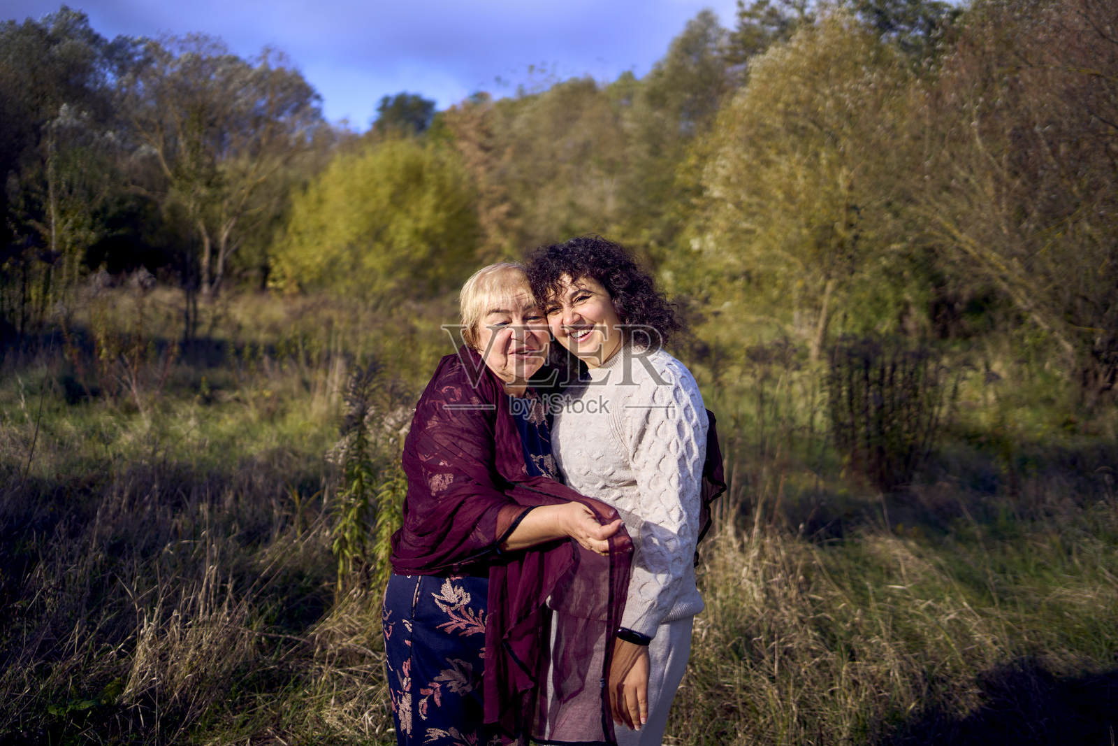 中年女儿与年迈母亲在秋季森林中散步照片摄影图片