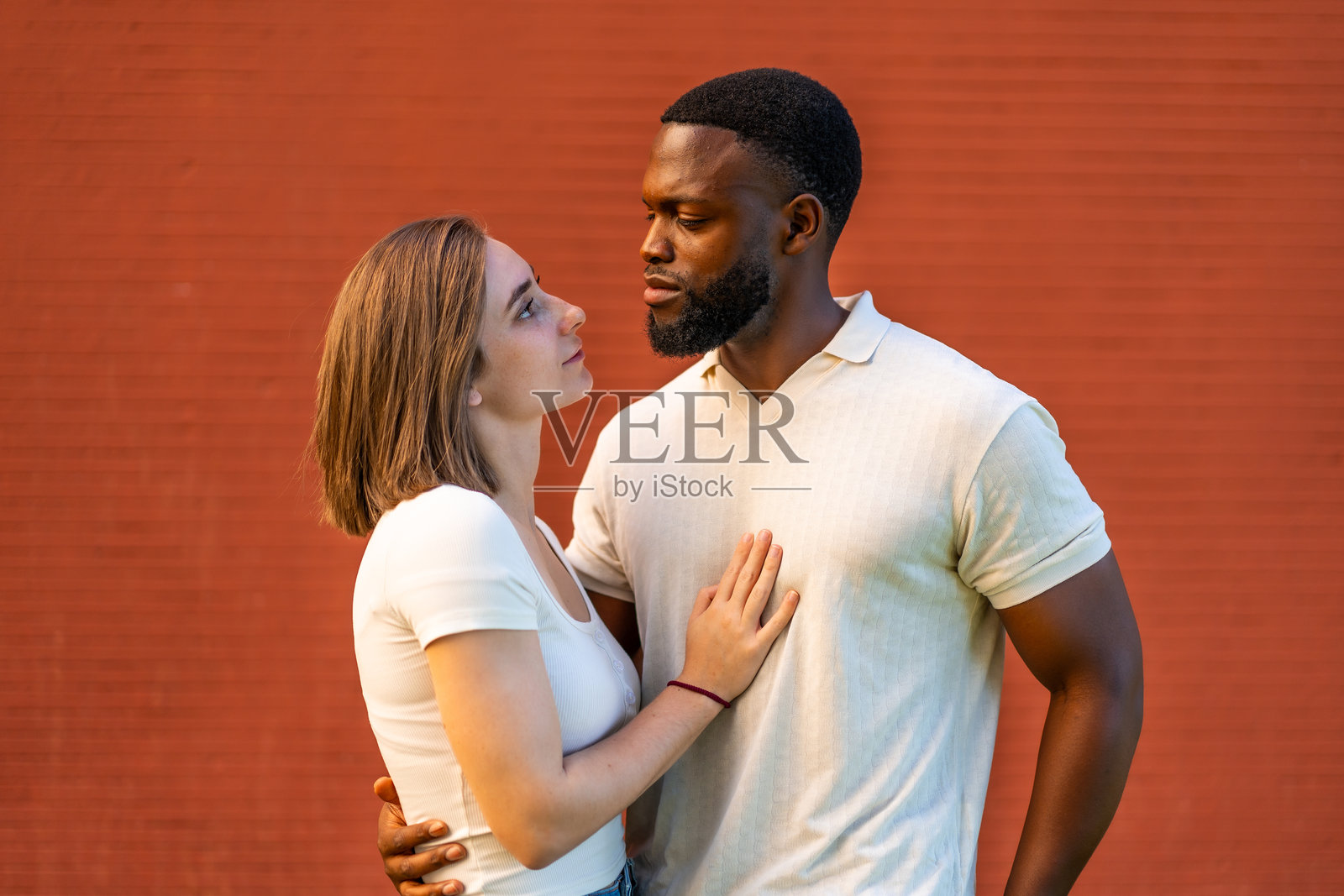 混血情侣相拥而立,互相凝视。照片摄影图片