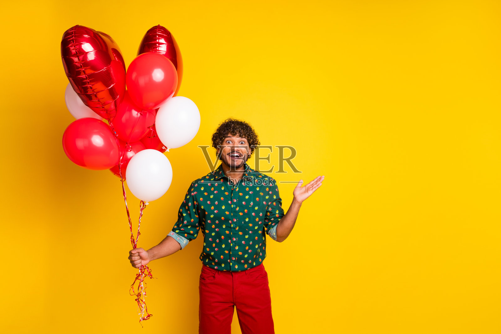 兴奋、快乐、优雅的男人穿着时尚的衣服,手持氦气球,背景为黄色。照片摄影图片