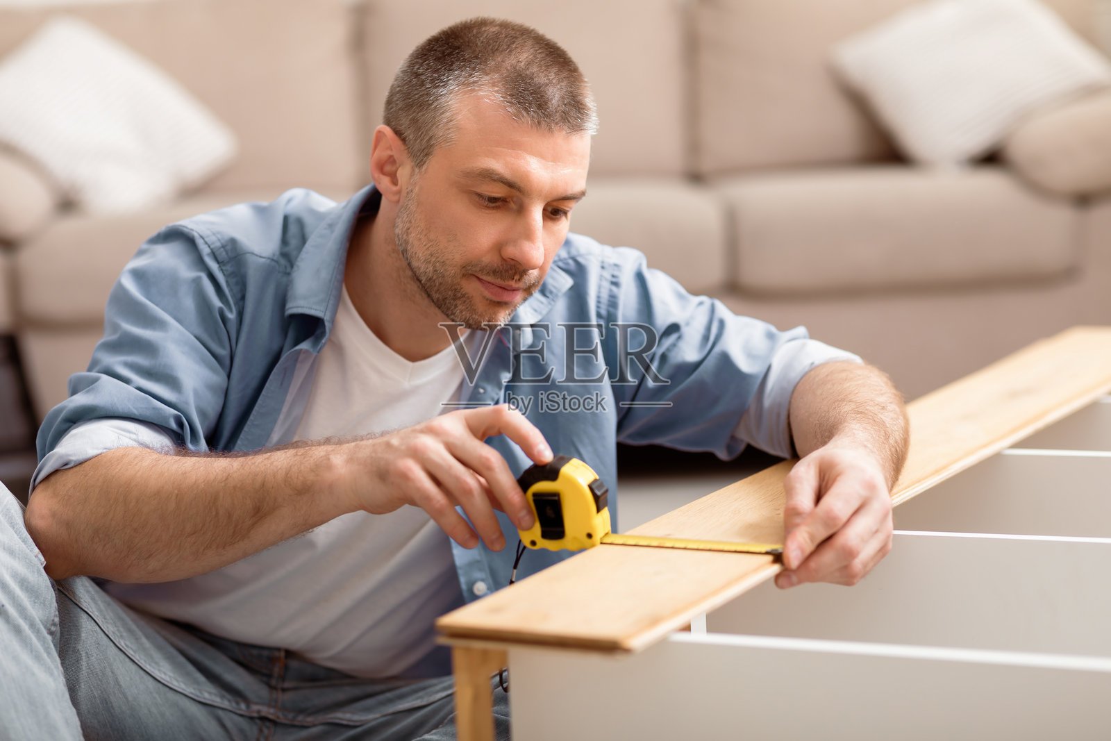 成熟男性在家中组装书架并用卷尺测量照片摄影图片