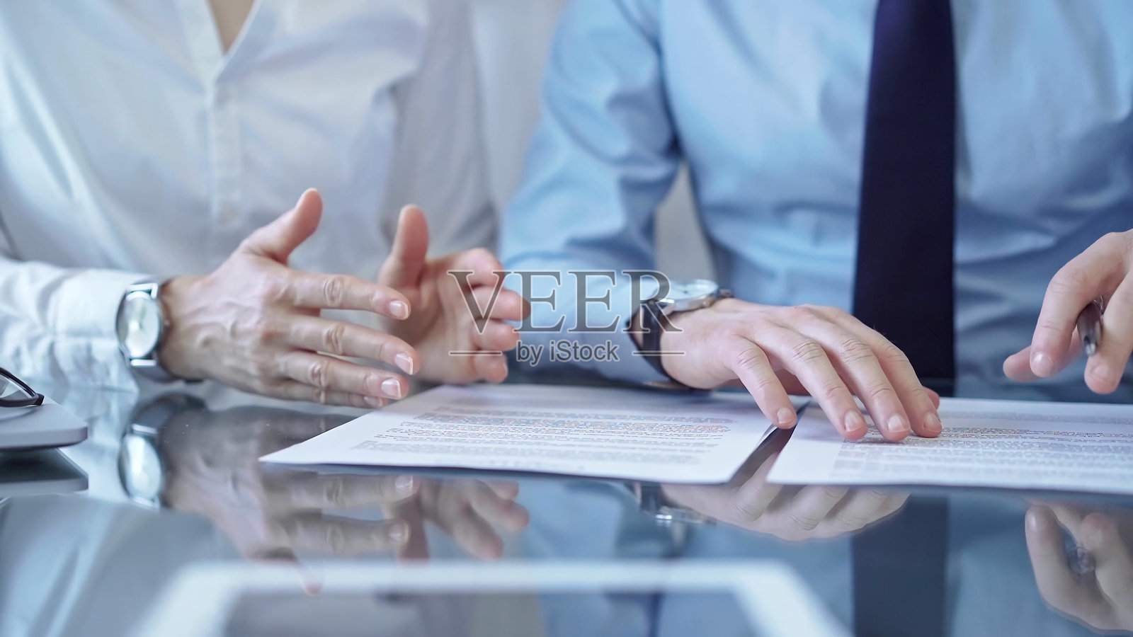 多元化的商务人士在签署合同前讨论文件。律师团队在办公室的玻璃桌前工作。照片摄影图片