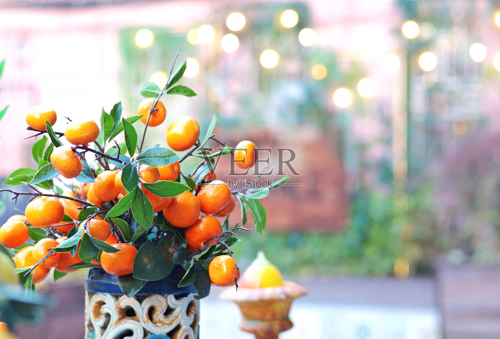 桌子上的陶瓷花瓶里插着橘子枝。照片摄影图片