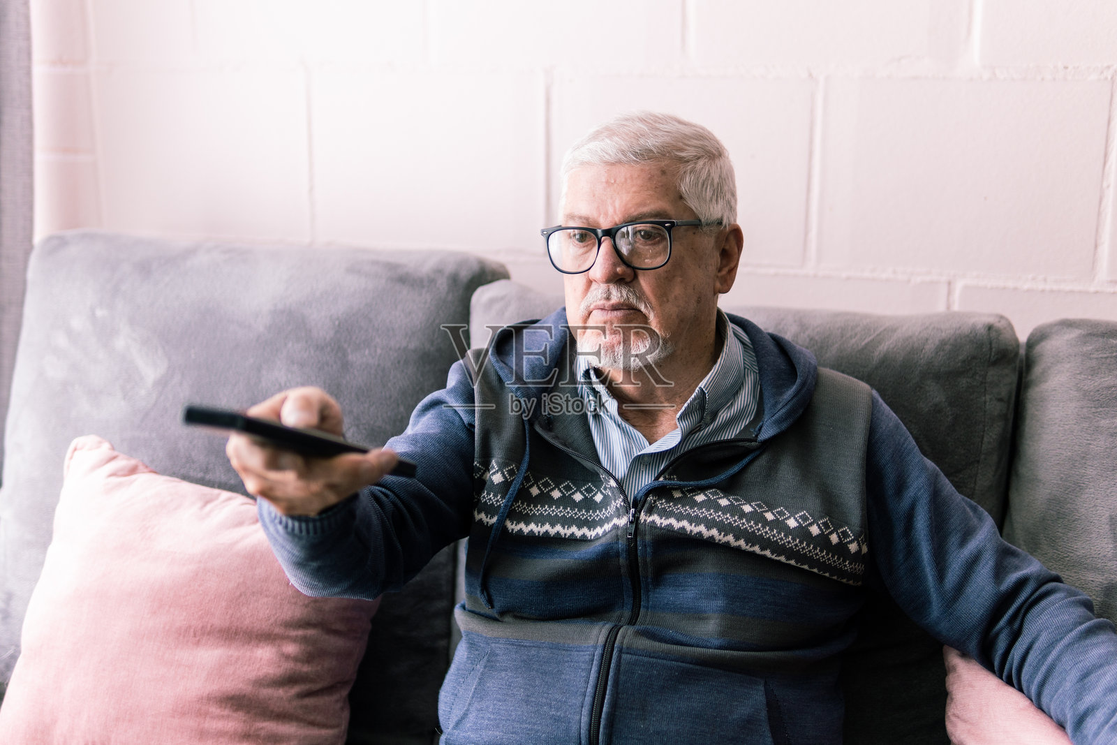 坐在沙发上的老人指着遥控器照片摄影图片
