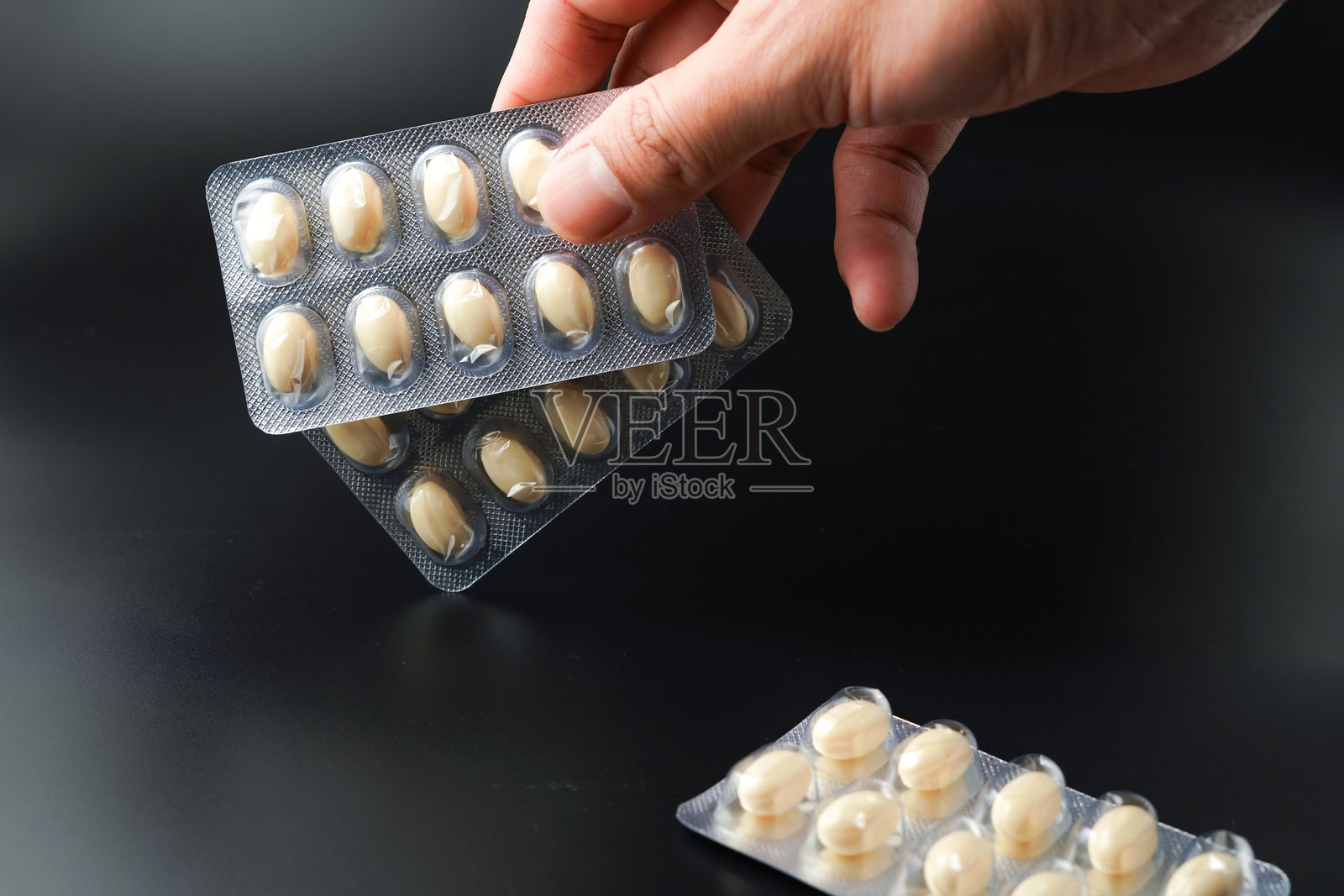 男子手持含有Omega、维生素E、鳕鱼肝油和DHA的白色软胶囊鱼油泡罩包装。照片摄影图片