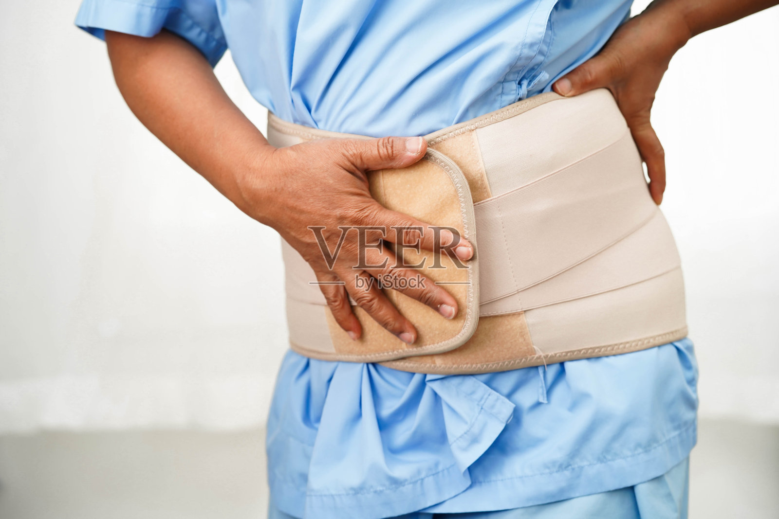 亚洲老年人背部疼痛,佩戴弹性支撑带,使用助行器。照片摄影图片