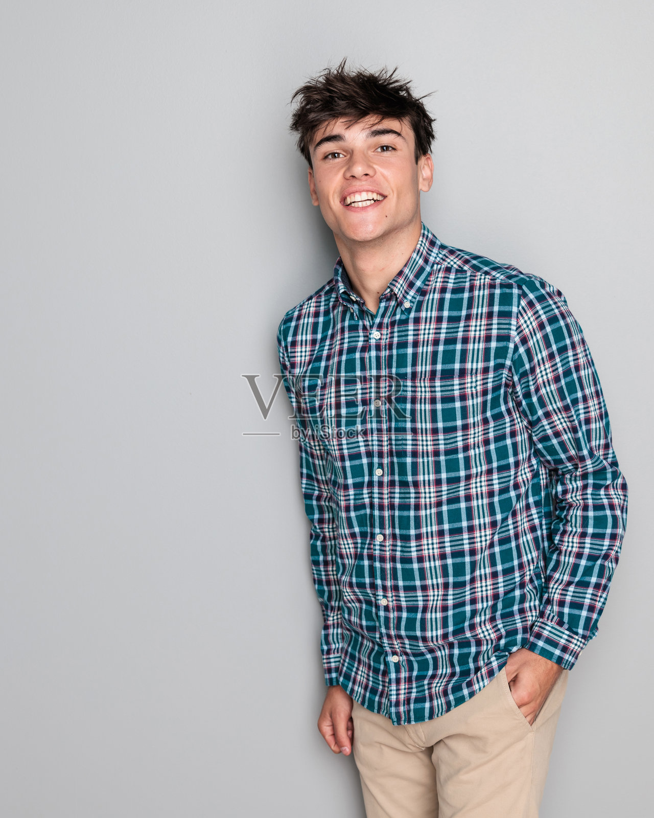 自信的休闲男子穿着格子衬衫,双手插在口袋里,面带笑容。照片摄影图片