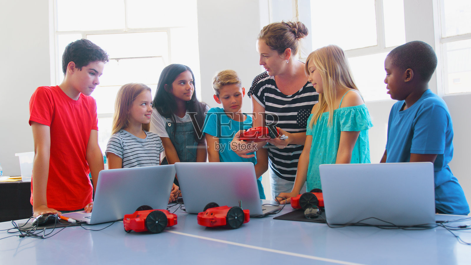一群学生在学校的计算机编程课上与女老师一起学习编程机器人车辆照片摄影图片
