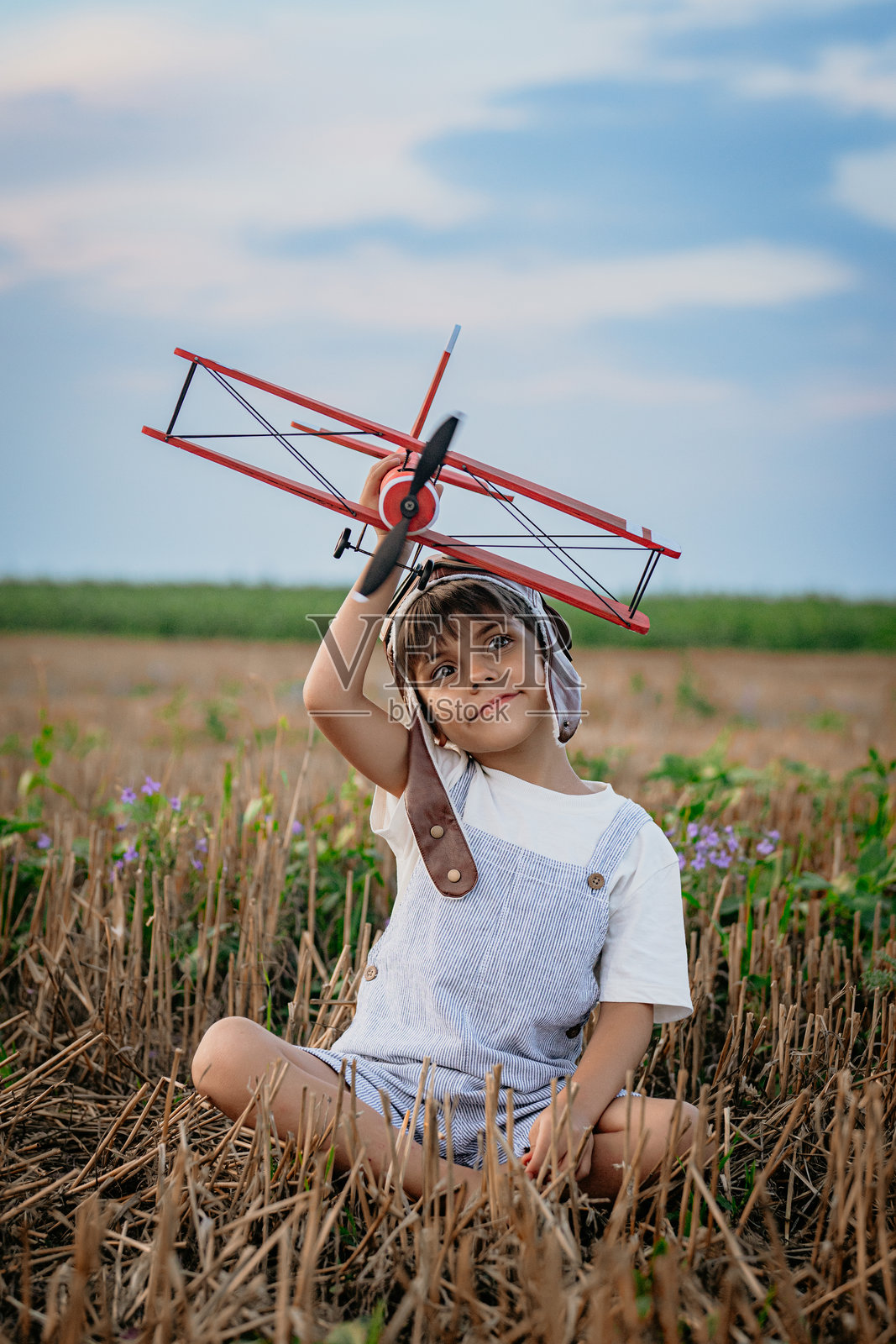 微笑着的5岁男孩对木制飞机感兴趣,探索未来职业的兴趣,梦想成为飞行员,夏天的田野上旅行。创造性的梦想,幻想,童年。照片摄影图片