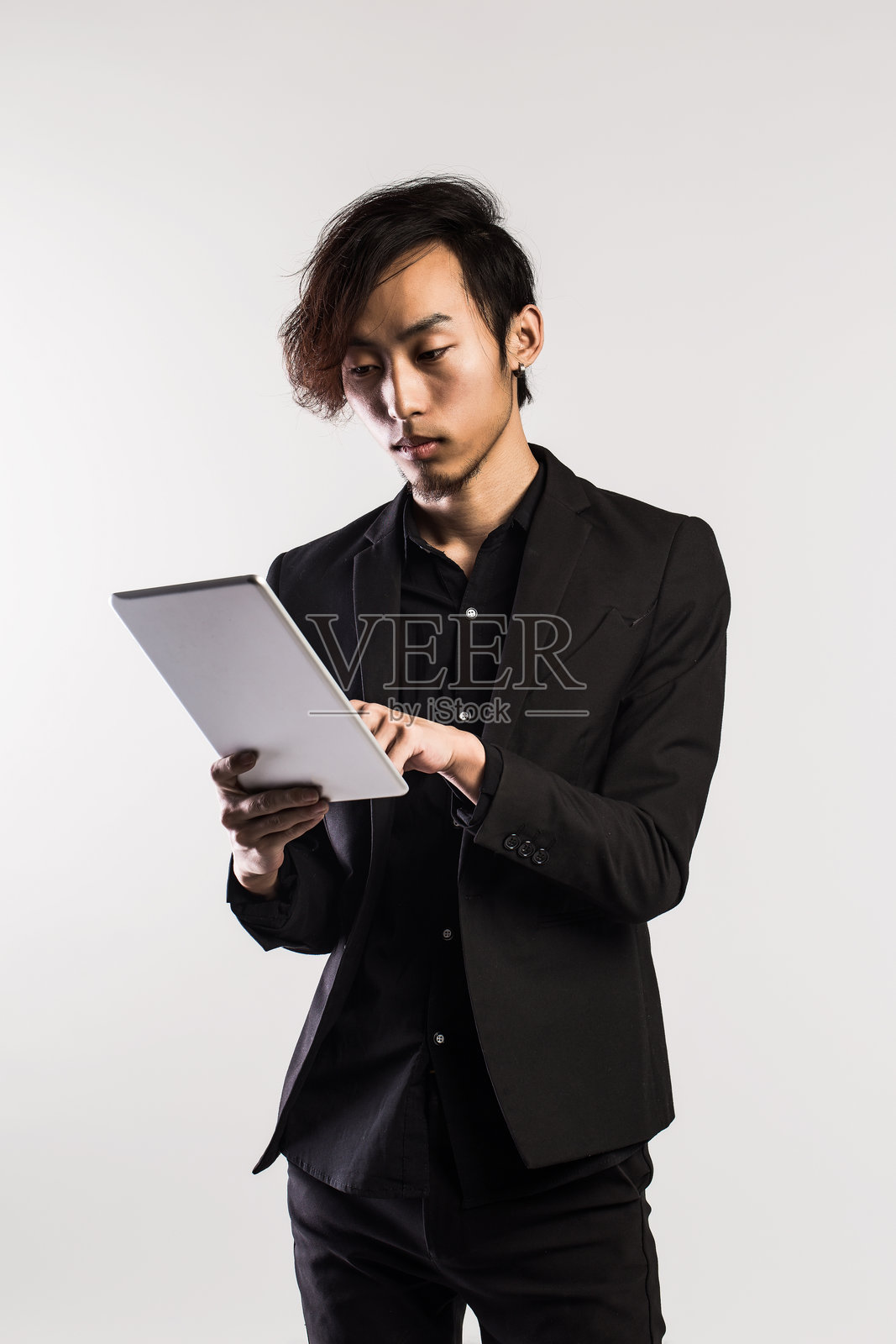 严肃的年轻男性高管在灰色背景下使用数字平板电脑照片摄影图片