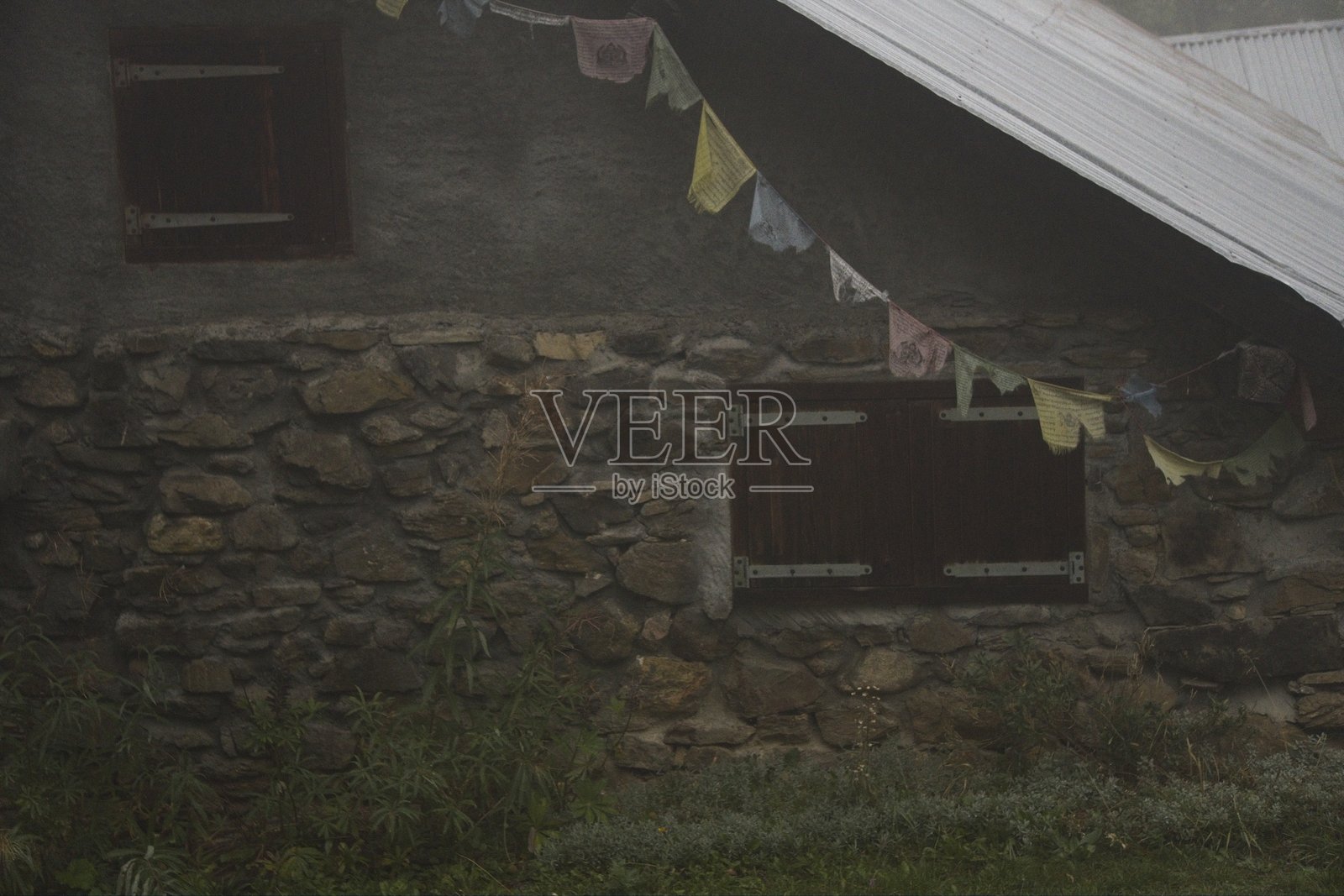 雾中的藏族旗帜与山石房屋照片摄影图片