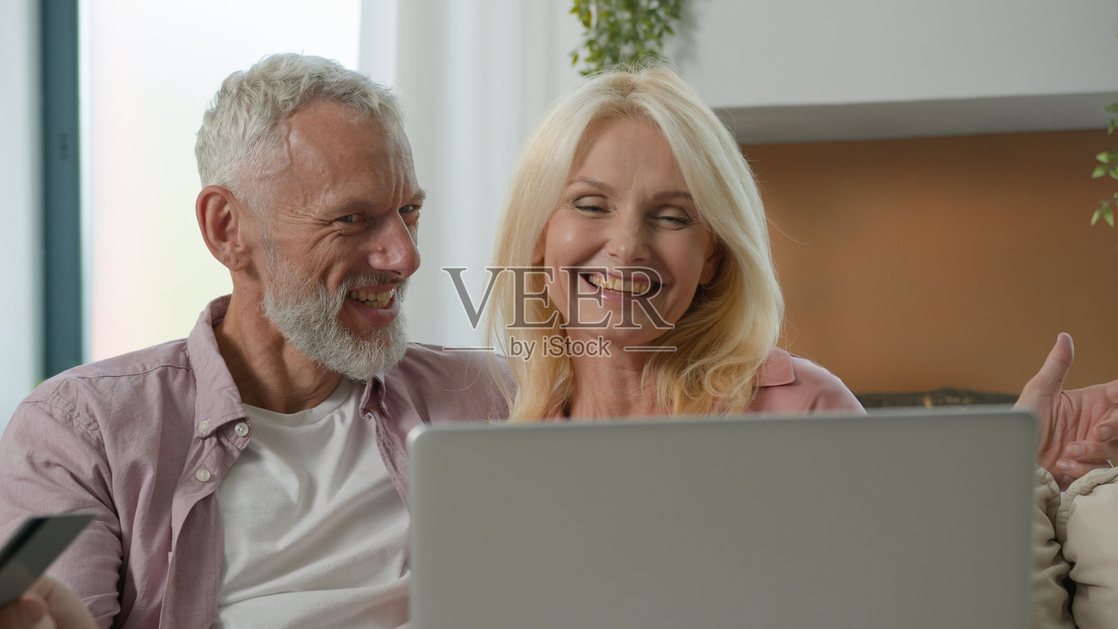 快乐的老年白人夫妇在家中使用笔记本电脑通过互联网支付养老金,安全地在网上商店购物。照片摄影图片