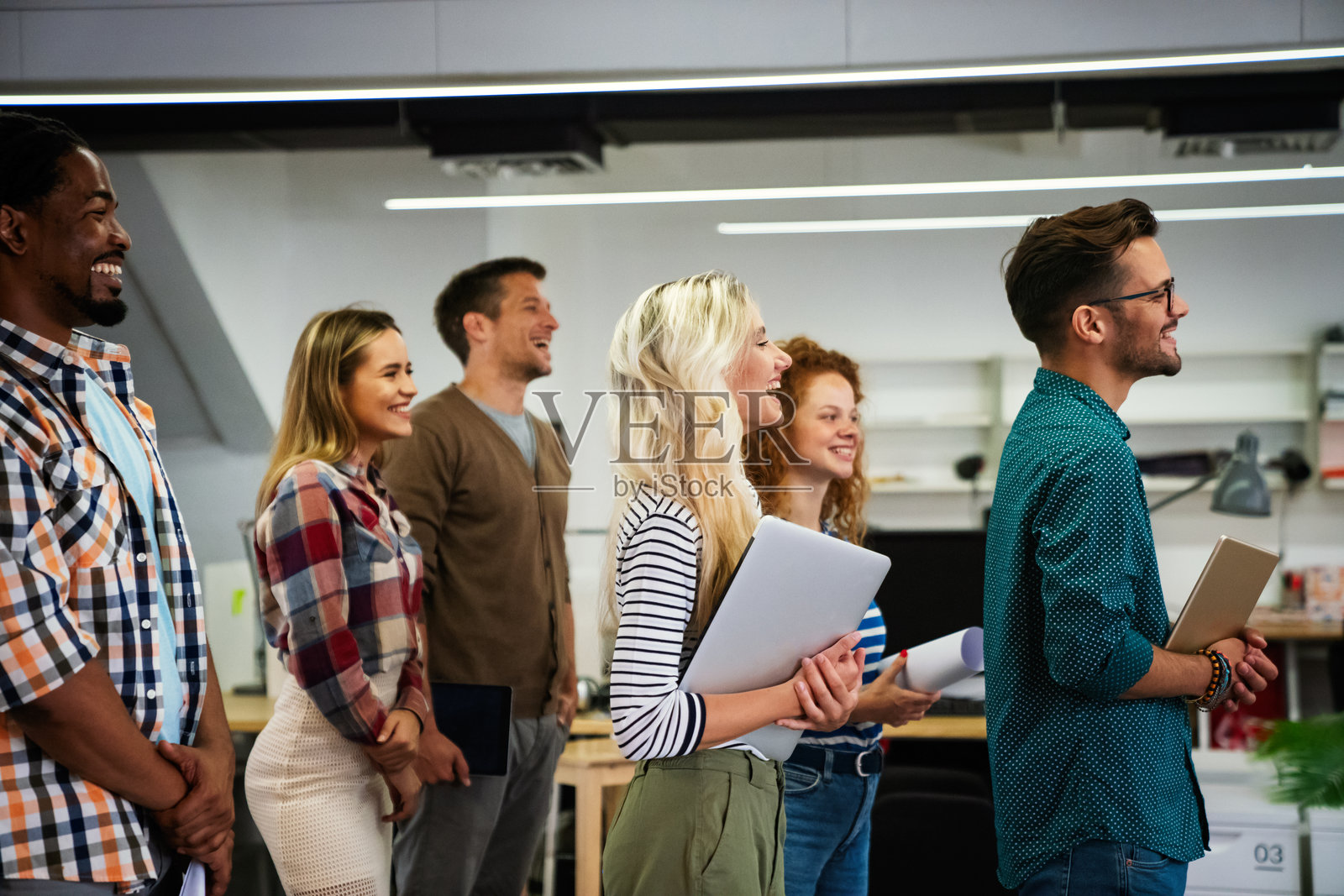 微笑的多元化同事们聚集在会议室,共同讨论财务统计数据。照片摄影图片