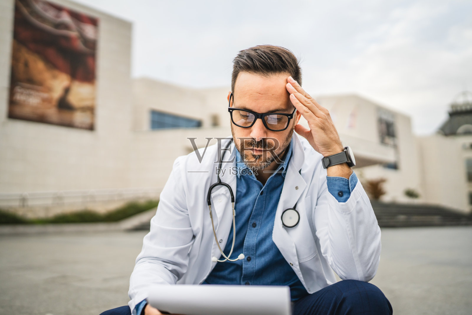 疲惫且担忧的医生在查看夹板上的信息照片摄影图片