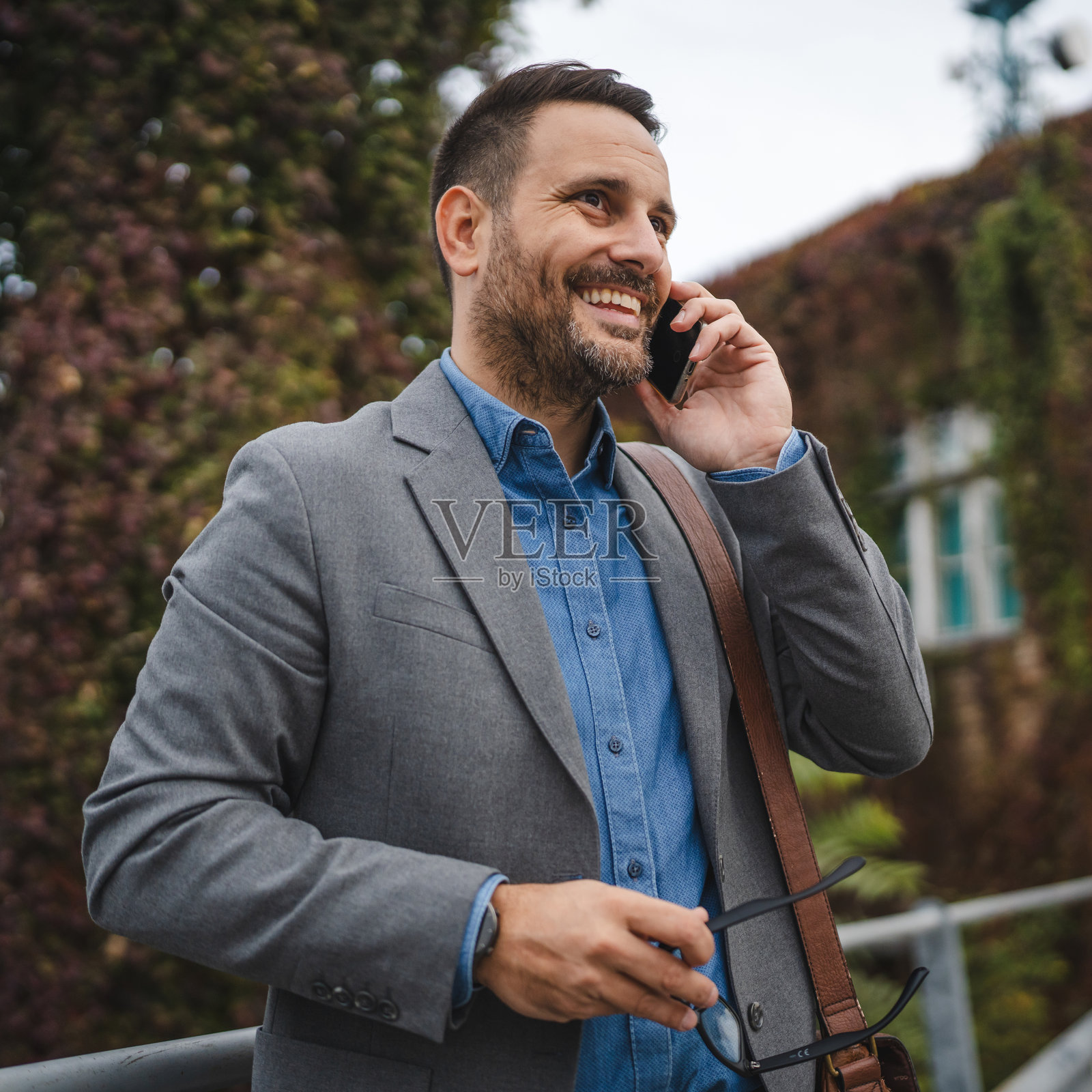 微笑的成年男性商人在露台上打电话照片摄影图片