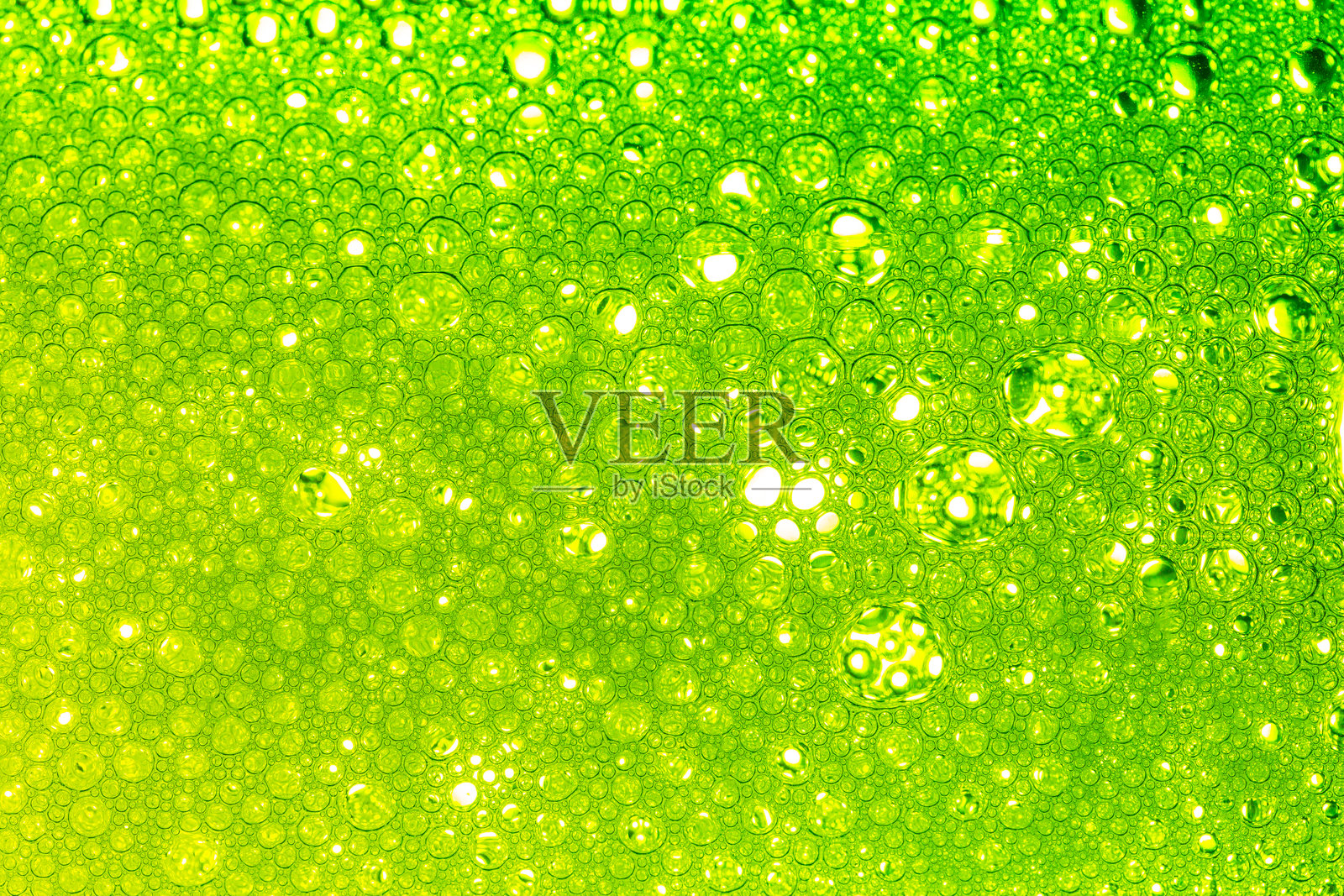 绿色宏观气泡,浅绿色背景,水中油滴的特写。液体表面气泡的抽象宏观照片。明亮的结构性水纹理设计。照片摄影图片