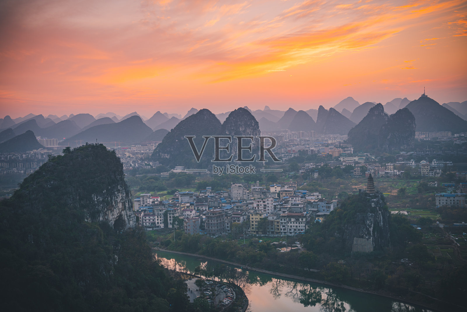 山丘上的古塔,周围环绕着石灰岩山脉和城市建筑照片摄影图片