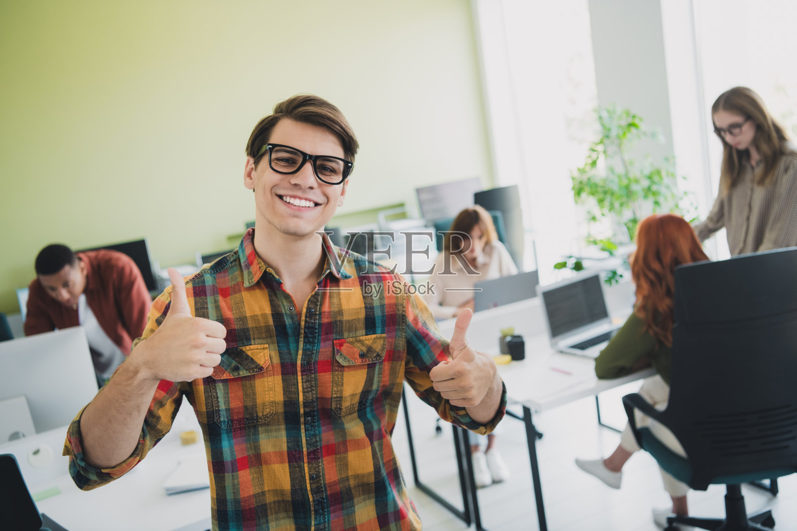 年轻的IT同事们在室内工作坊中愉快友好地竖起大拇指,享受共同的职业教育。照片摄影图片