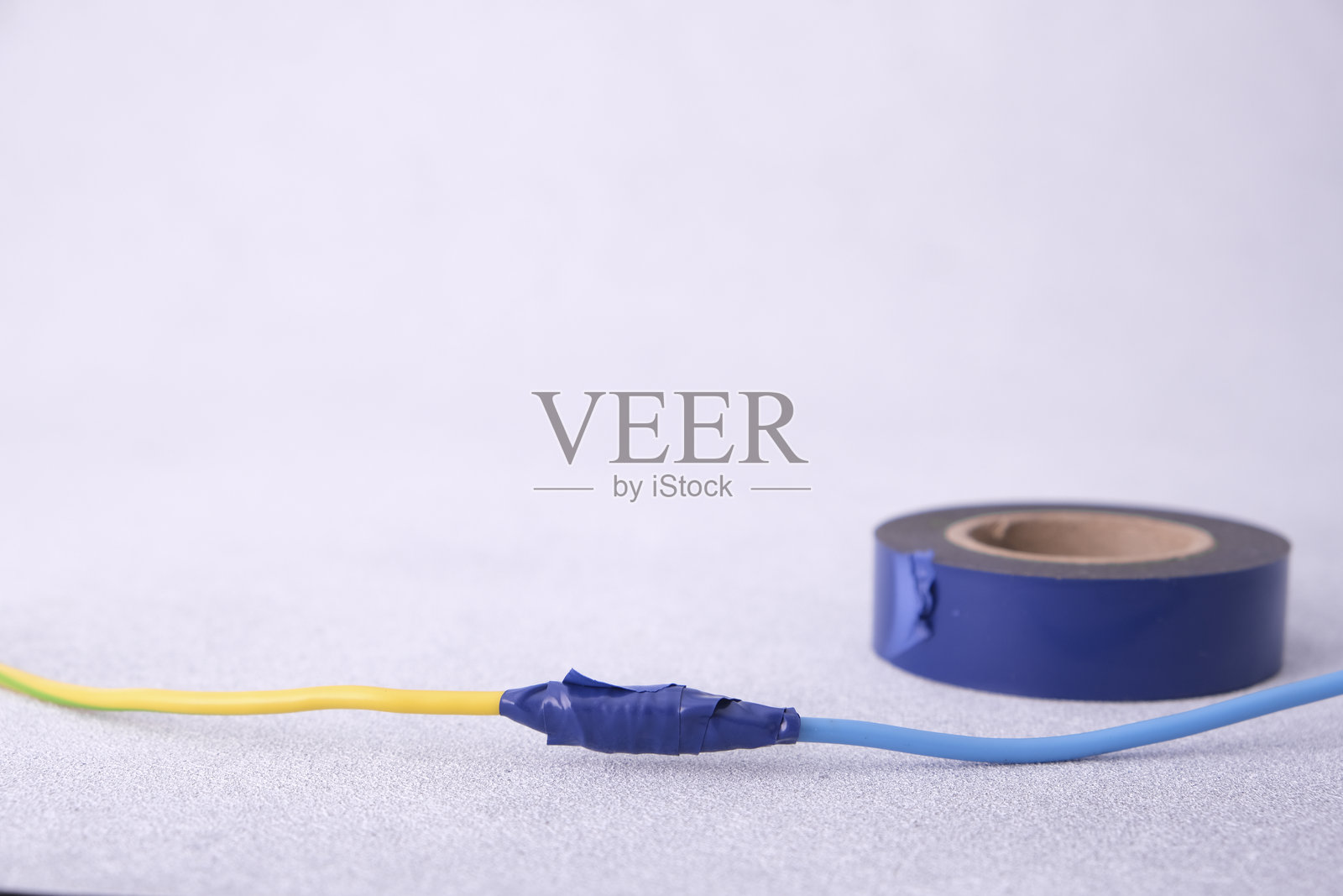 用电工胶带连接两根绝缘电线。照片摄影图片